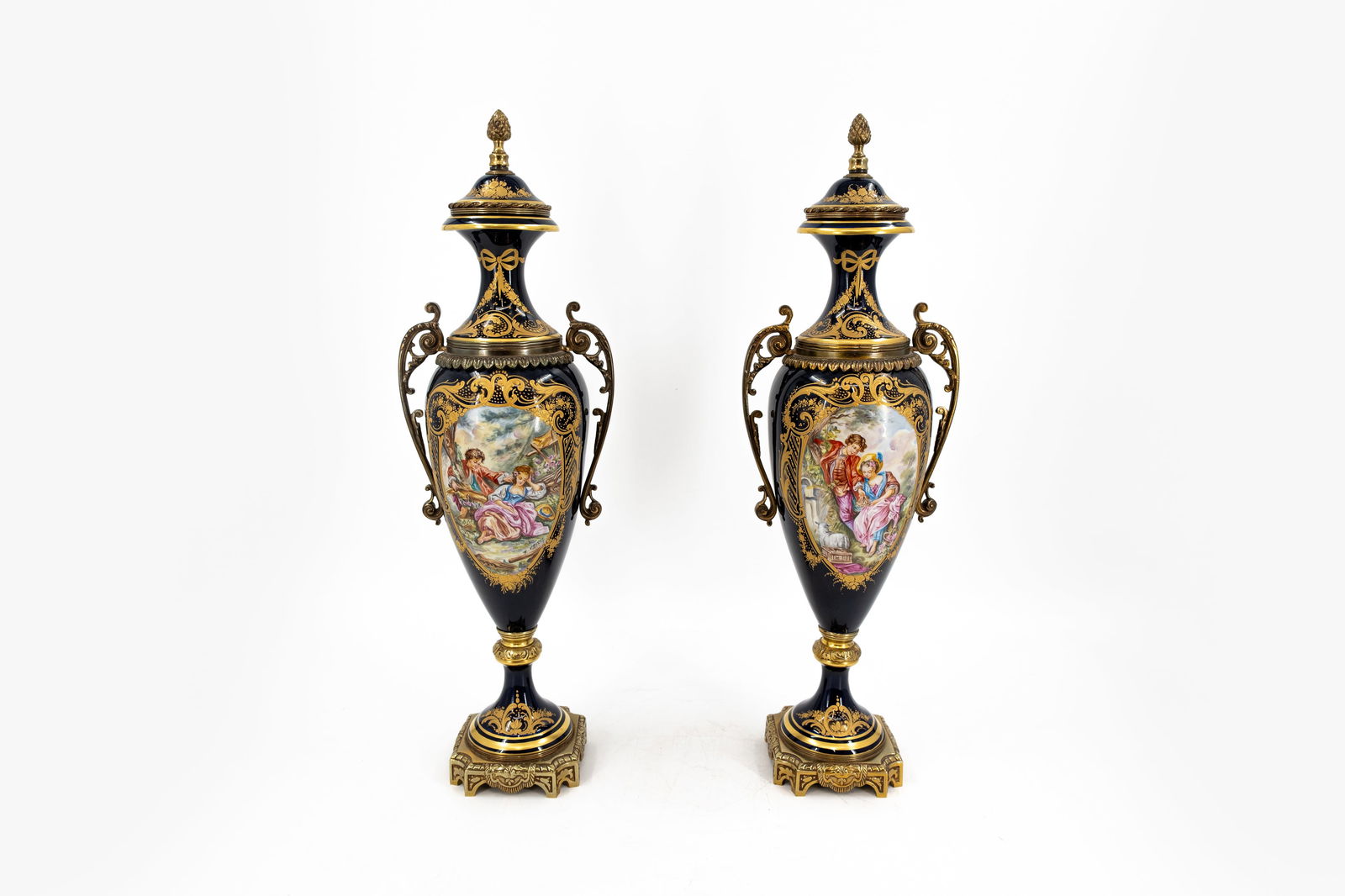 A pair of French Sevres style cobalt porcelain vases decorated with hand painted scenes: A pair of French Sevres style cobalt porcelain vases decorated with hand painted scenes, gilt brass mountings and mounted covers. Signed, 20th century. H: 54 cm