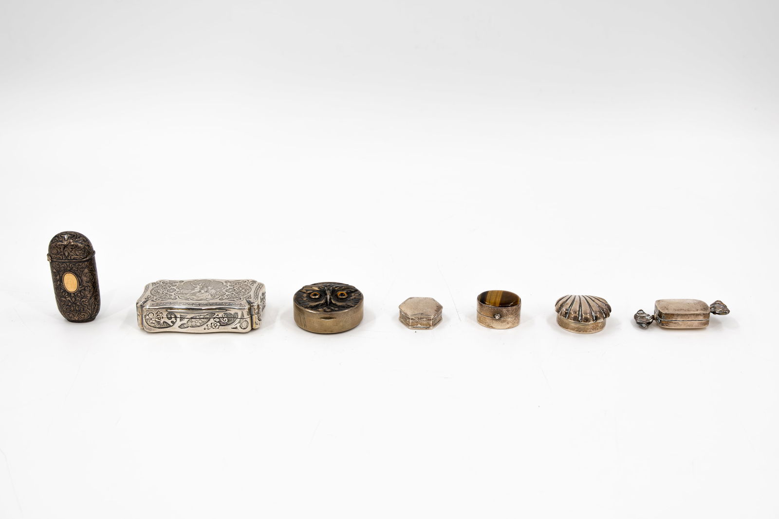A collection of seven variously shaped and decorated silver pill and snuff boxes: A collection of seven variously shaped and decorated silver pill and snuff boxes. Hallmarks, 19th/20th century. W: 2,8 - 7,8 cm, smallest to largest