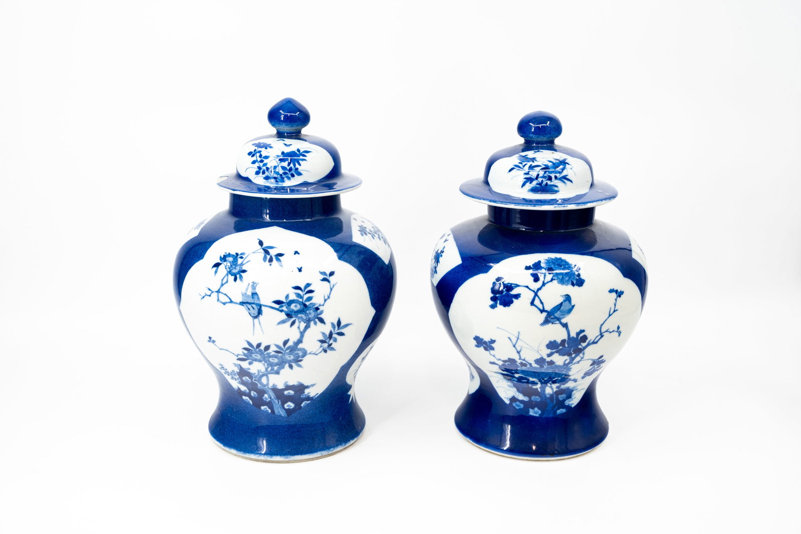 A lot of two matching Chinese blue and white bird and flora decorated covered porcelain vases: A lot of two matching Chinese blue and white on a blue poudre background bird and flora decorated covered porcelain vases. Bottom has a double circle mark. 19th century. Condition: one cover has a rim