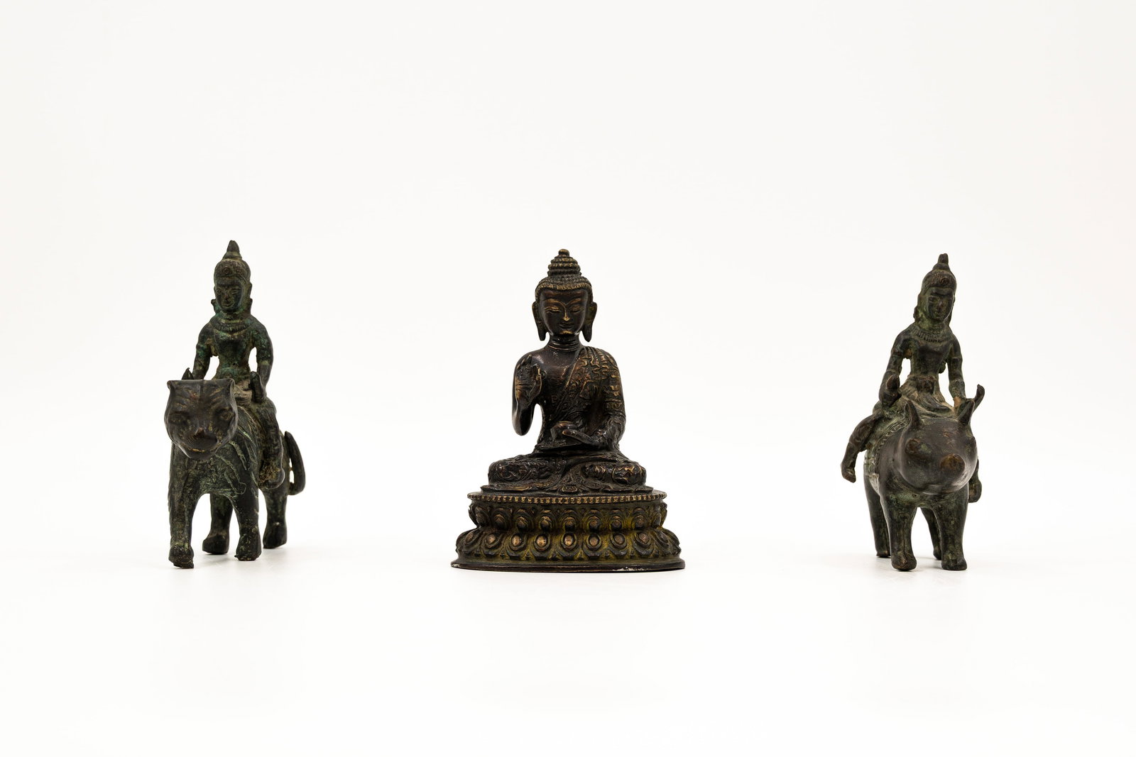 A composed lot of three Tibetan patinated bronze figures: A composed lot of three Tibetan patinated bronze figures of sitting Buddha and a man on a tiger and a pig. 19th/20th century. H: 14 cm