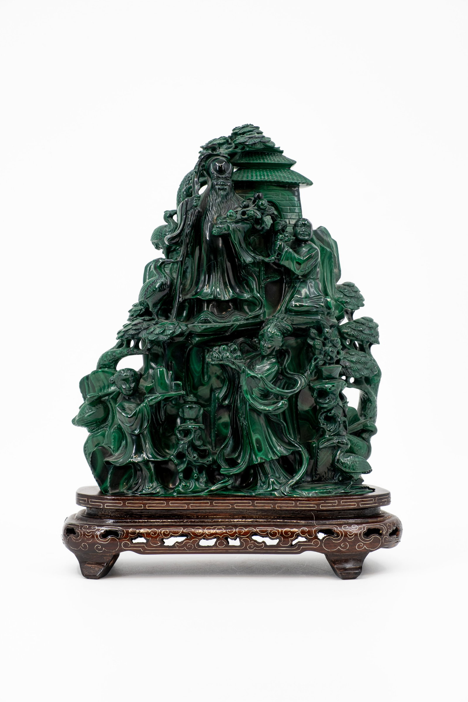A Chinese finely carved malachite stone figural sculpture group: A Chinese finely carved malachite stone figural sculpture group depicting an immortal and lady with the children in a nature scene. Footed on a carved wooden and inlay base. 19th/20th century. H: 26 -