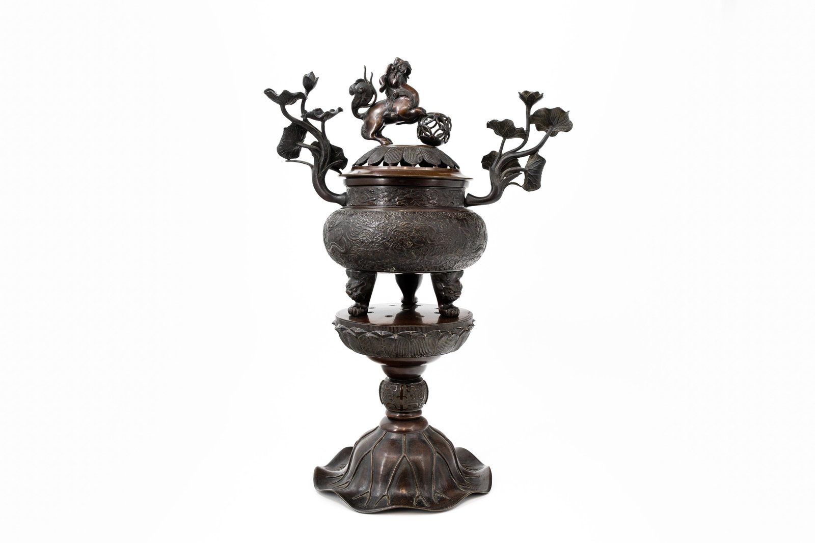 An antique oriëntal patinated bronze tripod covered incense burner on matching base: An antique oriëntal patinated bronze tripod covered incense burner with figure of a lion on top and finely reliëf decorated with dragon scene. Standing on a matching base Late 19th century. H: 64 cm