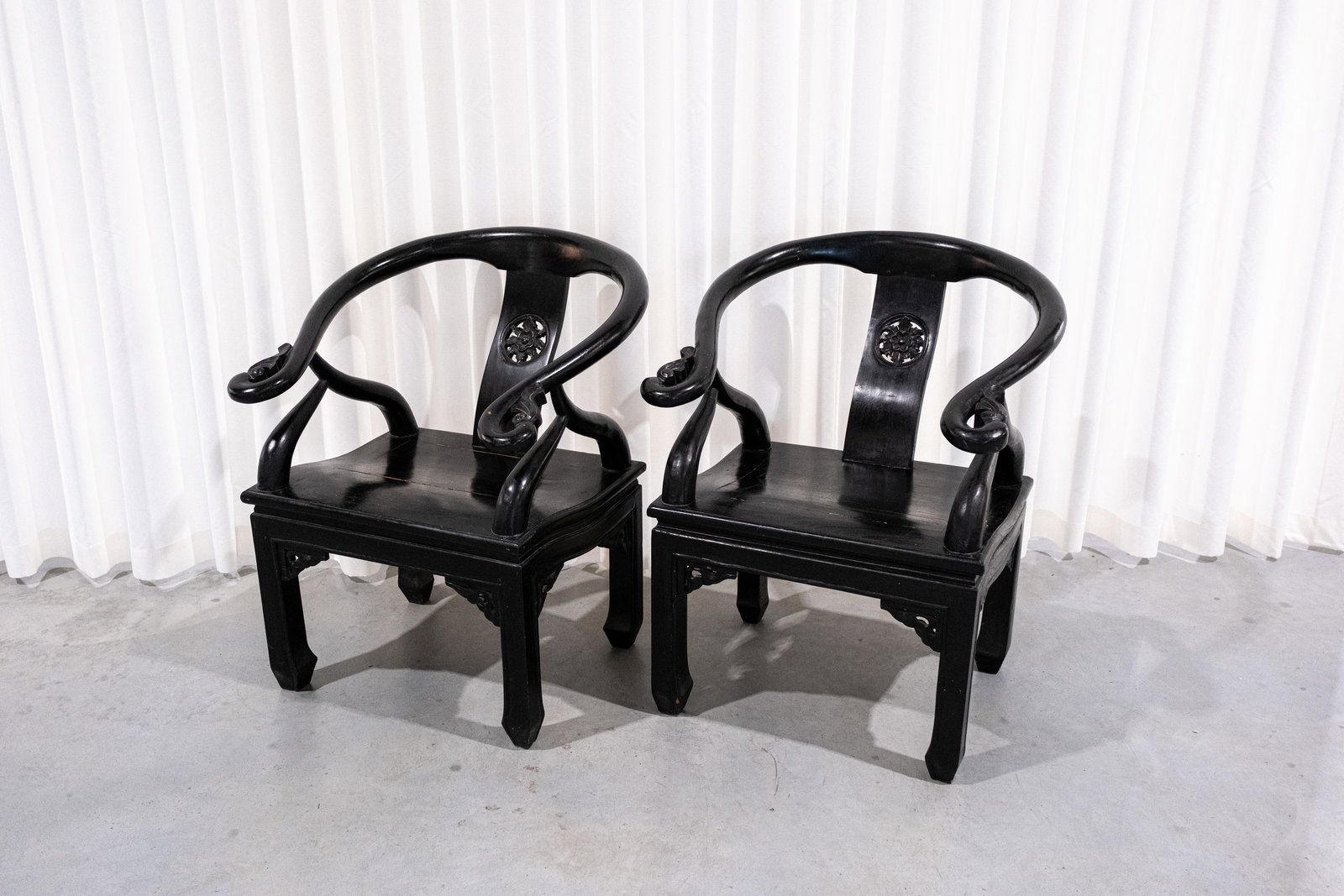A pair of Chinese carved decorated blackened wooden armchairs: A pair of Chinese carved decorated blackened wooden armchairs. 20th century. H: 86 - W: 66 cm