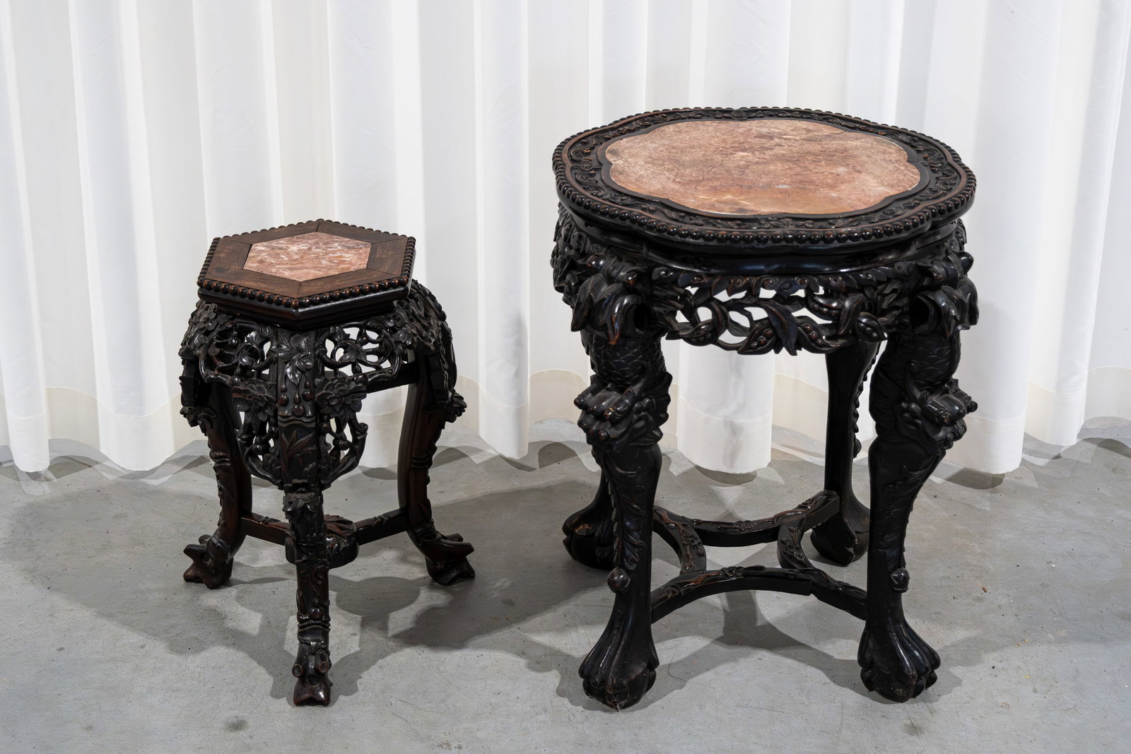 A composed lot of two Chinese finely carved hardwood various shaped pedestals: A composed lot of two Chinese finely carved hardwood various shaped pedestals with a red marble top. Late 19th century. H: 47 - 58 cm