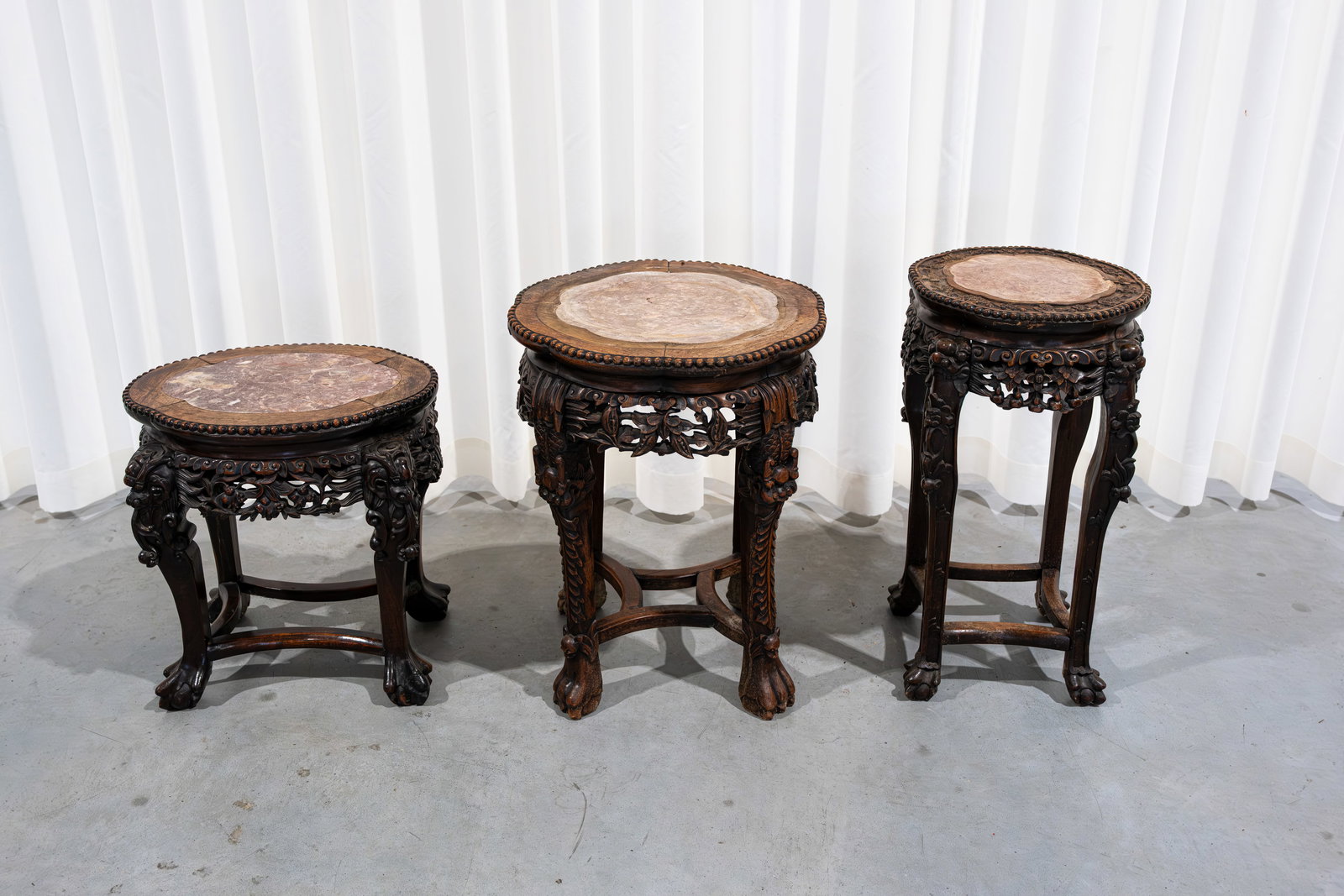 A composed lot of three Chinese carved hardwood pedestals: A composed lot of three Chinese variously shaped and carved hardwood pedestals with a red marble top. Late 19th century. H: 46 - 57 - 61 cm