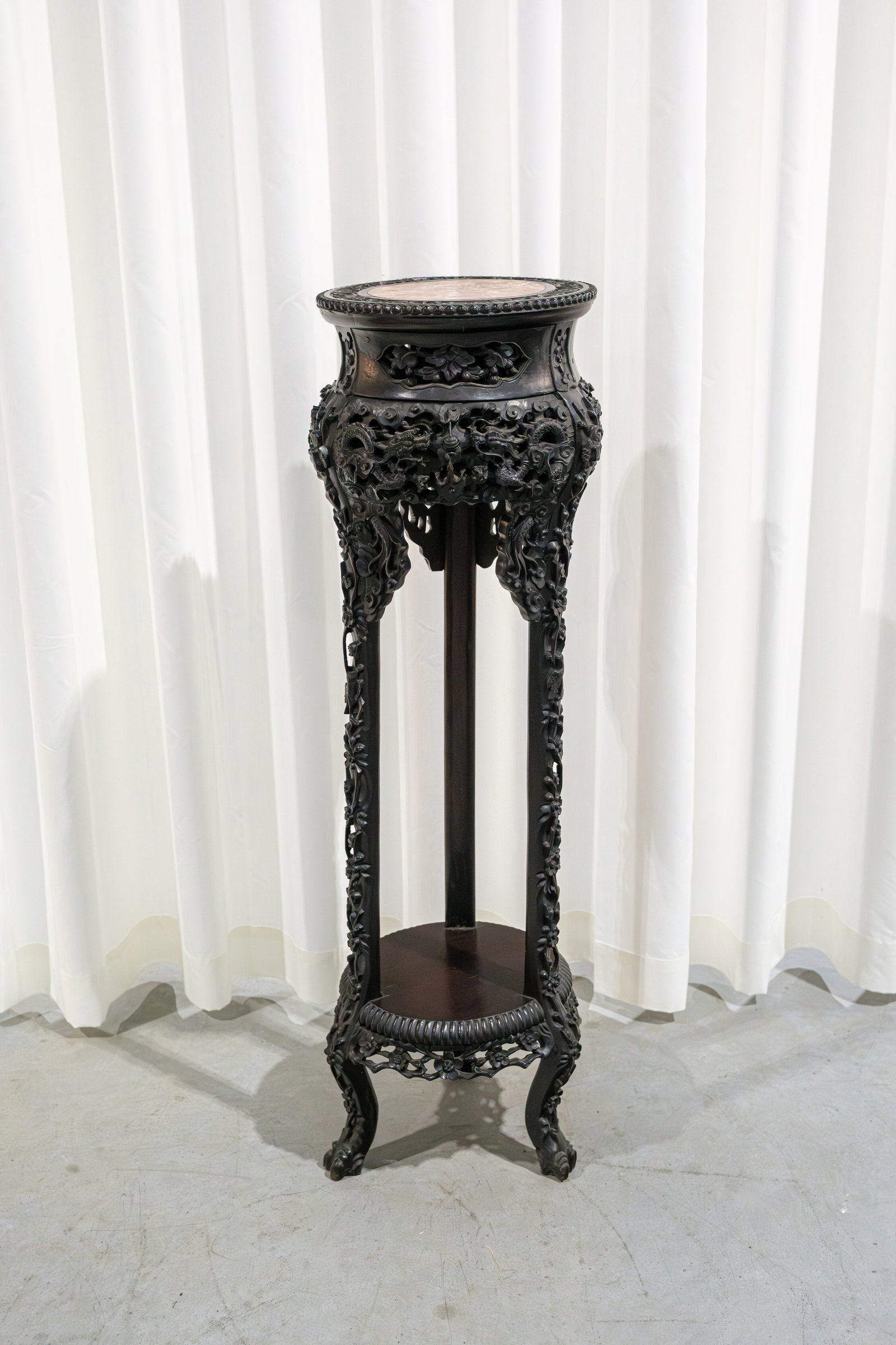 A Chinese carved hardwood pedestal with red marble top and finely decorated with a dragon scene: A Chinese carved hardwood pedestal with red marble top finely decorated with a dragon scene. Late 19th century. H: 104 cm