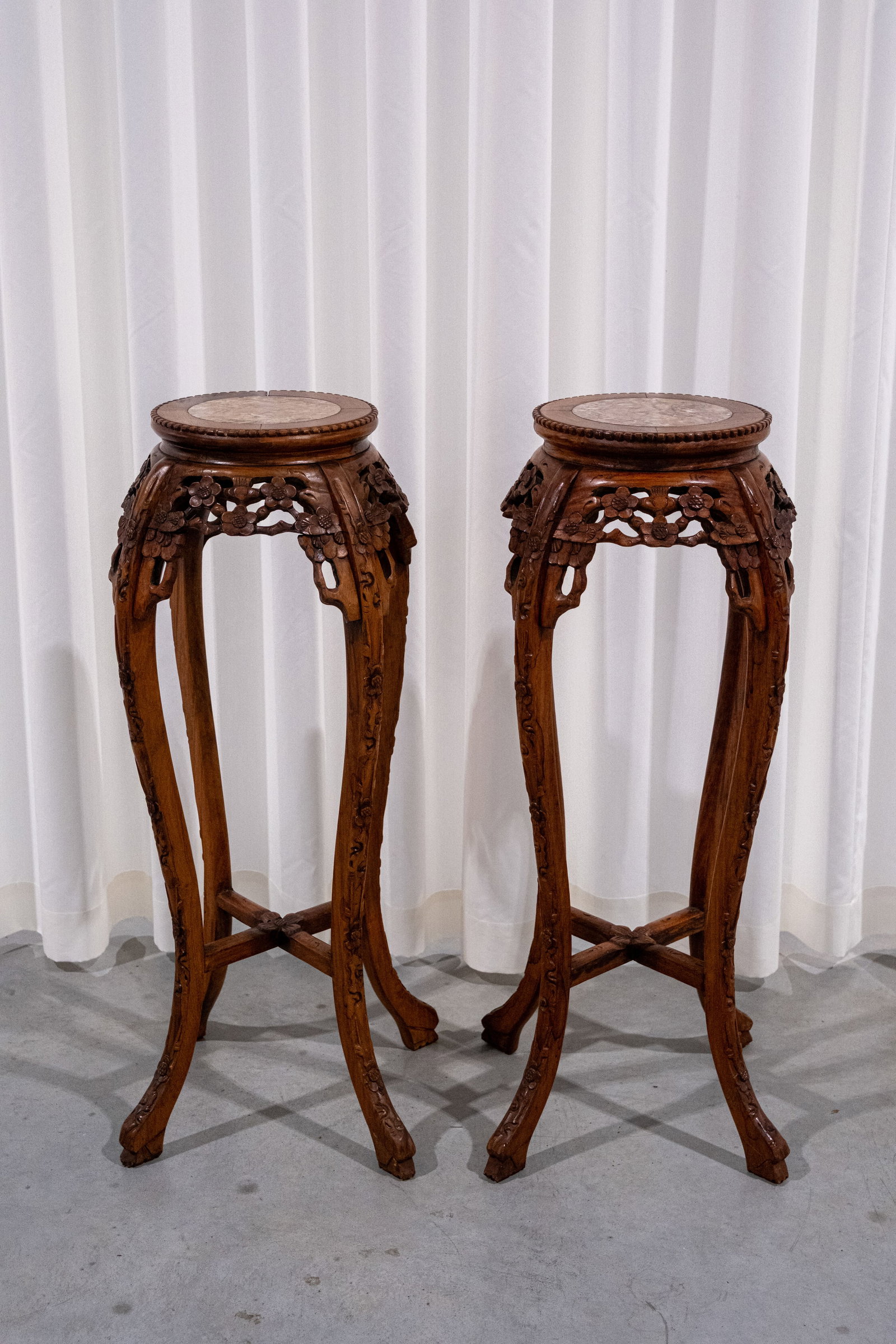 A matching pair of Chinese carved hardwood floral and blossoms decorated pedestals: A matching pair of Chinese carved hardwood floral and blossoms decorated pedestals with red marble tops. 20th century. H: 91 - W: 28 cm
