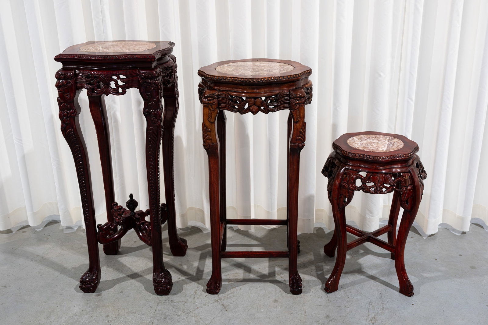 A composed lot of three Chinese carved hardwood various decorated pedestals: A composed lot of three Chinese carved hardwood various decorated pedestals with red marble tops. 20th century. H: 100 - 92 - 62 cm