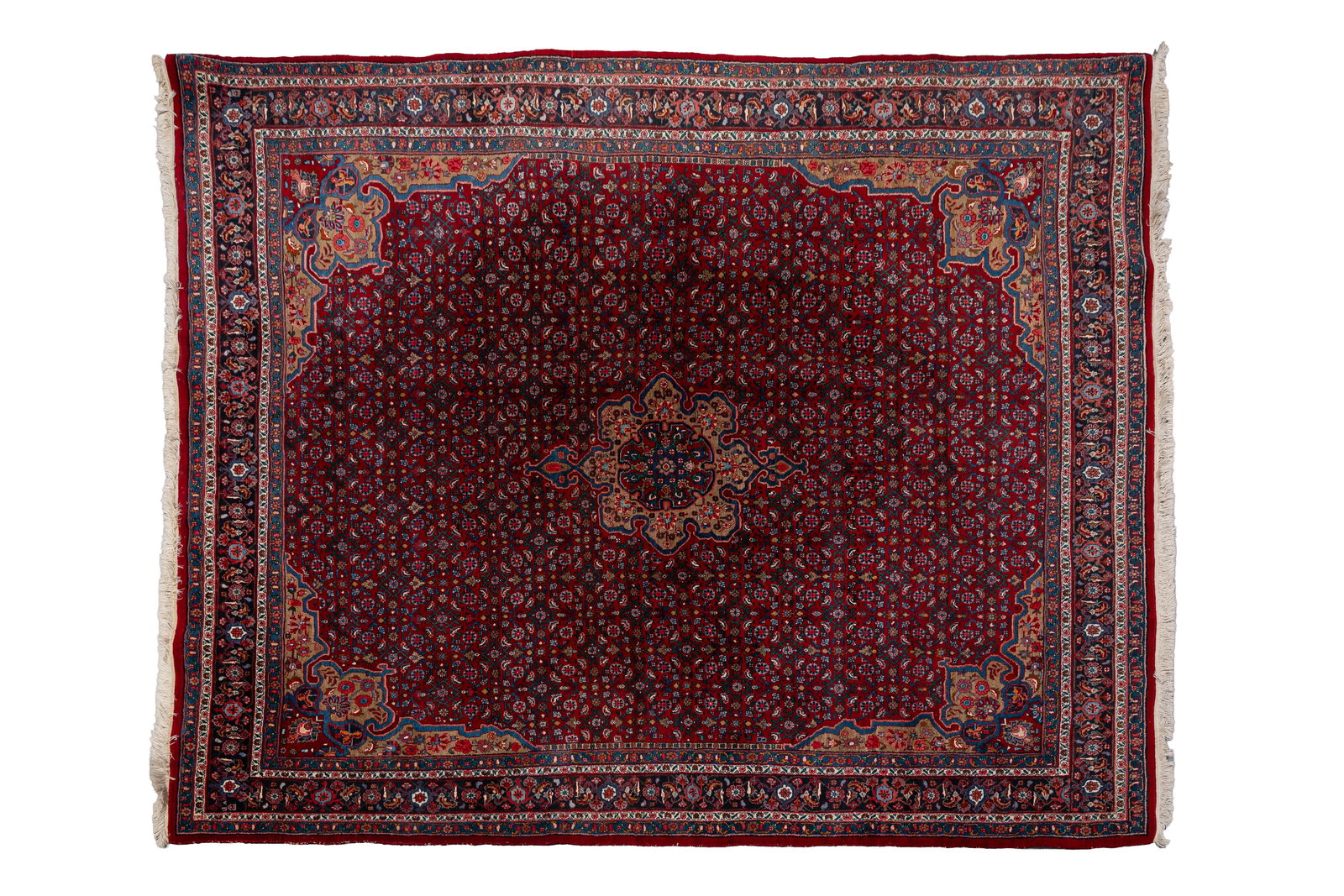 A large and hand-knotted Persian Oriental carpet with a central medallion: A large and hand-knotted Persian Oriental carpet with a central medallion on a deep red field. 20th century. L: 355 - W: 265 cm