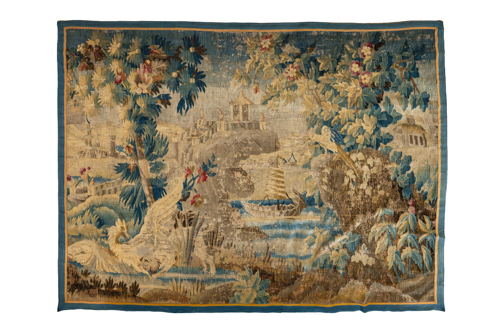 A large and antique hand-knotted European Flemish wool wall tapestry: A large and antique hand-knotted European Flemish wool wall tapestry depicting a landscape with exotic birds and a harbour scene. The tapestry shows some severe damages, condition report available on 