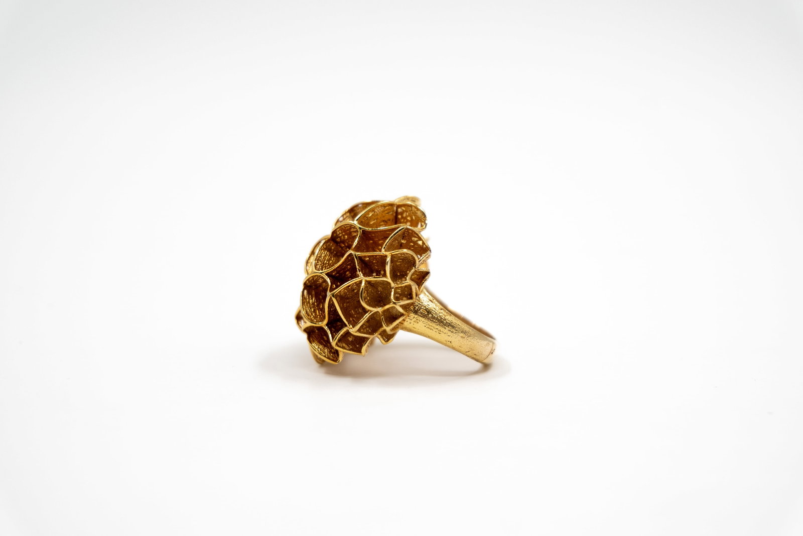 A modern 14k gold ring with sculptural floral design: A modern 14k gold ring with sculptural floral design. The raised flowerhead composed of openwork petal-shaped sections with textured gold surfaces, marked RB.