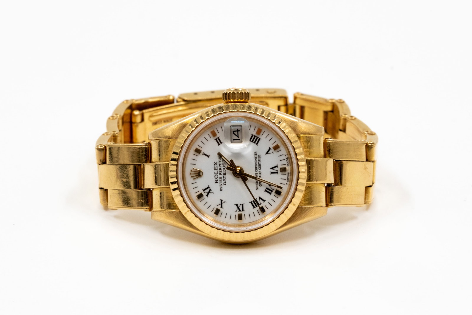 A ladies' 18k gold Rolex Oyster Perpetual Datejust wristwatch: A ladies' Rolex Oyster Perpetual Datejust wristwatch in 18k yellow gold, with white dial, Roman numeral hour markers, date aperture, gold bracelet and ribbed gold bezel. The clasp is marked Rolex, Swi