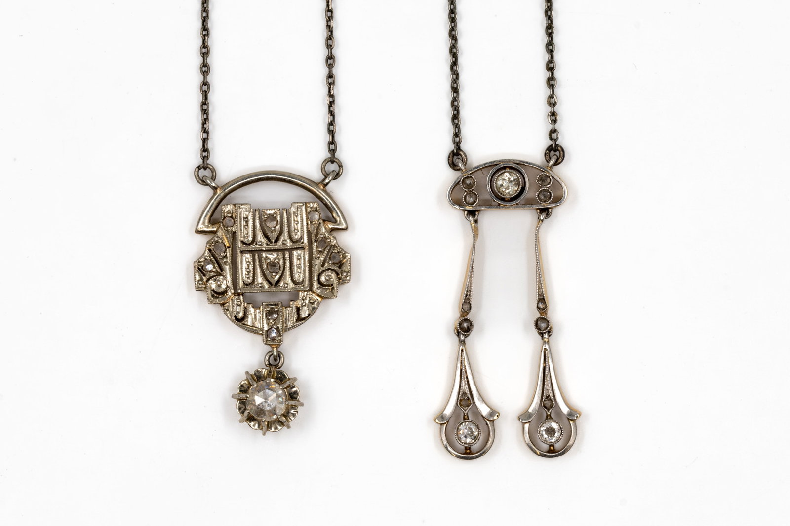 A composed lot of two 18k gold and silver pendant necklaces: A composed lot of two 18k gold and silver pendant necklaces. Comprising a gold and silver pendant necklace with geometric openwork design, set with small diamonds and suspending a rose-cut diamond dro