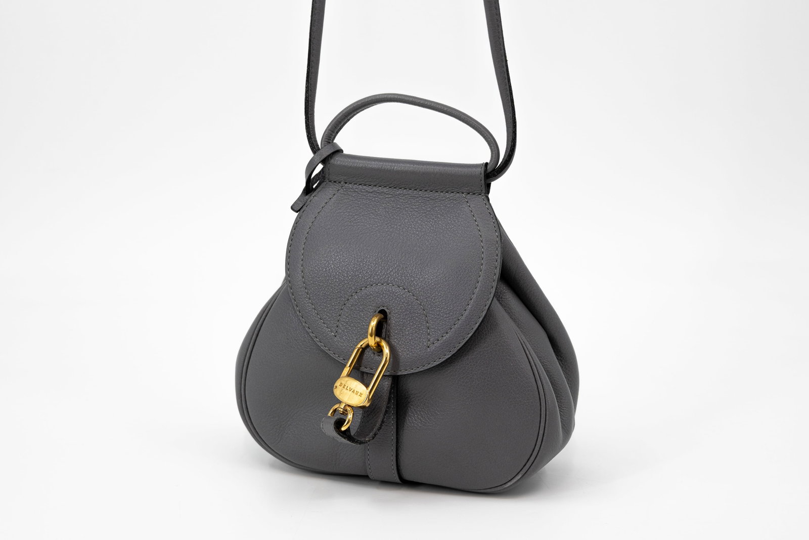 A Belgian Delvaux crossbody bag model Cerceau Mini in dark grey leather: A Belgian Delvaux crossbody bag model Cerceau Mini in dark grey leather with gold-toned hardware. The strap is adjustable. Comes with its Delvaux dustbag and vanity mirror. Condition: this bag is in v