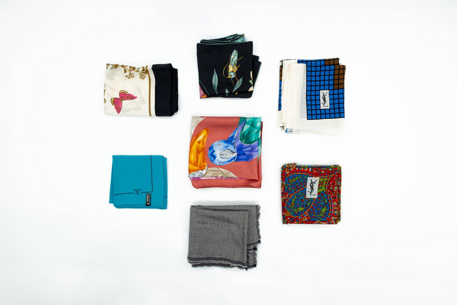 A composed lot of seven various designer scarves: A composed lot of seven various designer scarves with various motives and decorations. One Dior, two Yves Saint Laurent, two valentino and two Swarovski. Different fabrics and dimensions. Condition: t