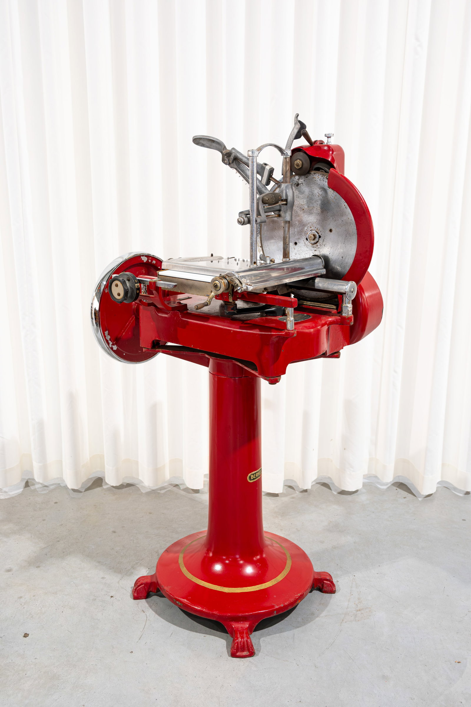 A vintage BERKEL meat slicer on its cast iron pedestal: A vintage BERKEL meat slicer on its cast iron pedestal. Marked and numbered. Circa 1950s. Used, but in fair condition, report available on request. H: 142 - W: 77 cm