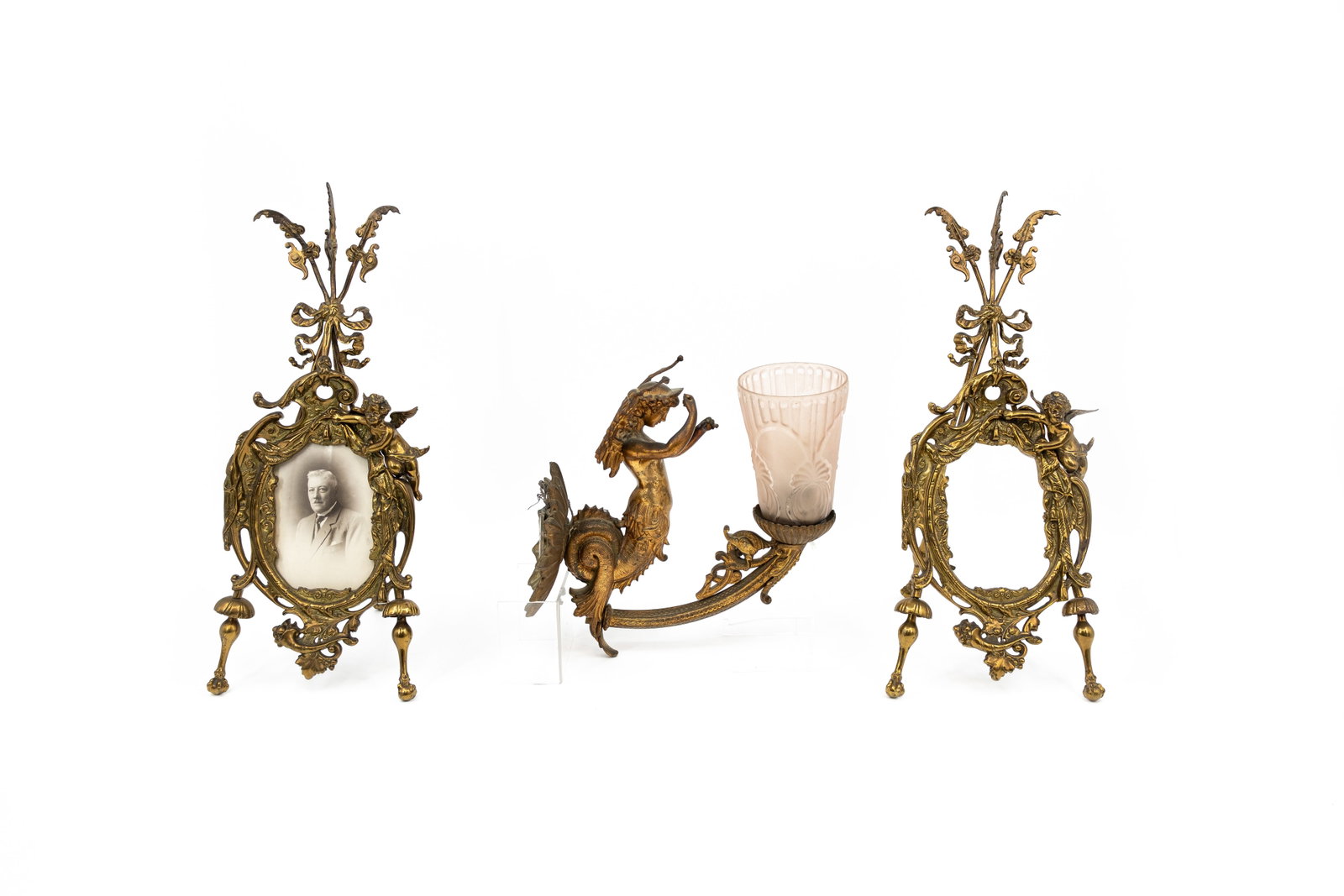 A composed lot of two antique brass decorated photo frames, together with one gilt brass wall: A composed lot of two antique brass decorated photo frames, together with one gilt brass wall lighting amplique. Circa 1900-1920s. H: 47 cm, frames