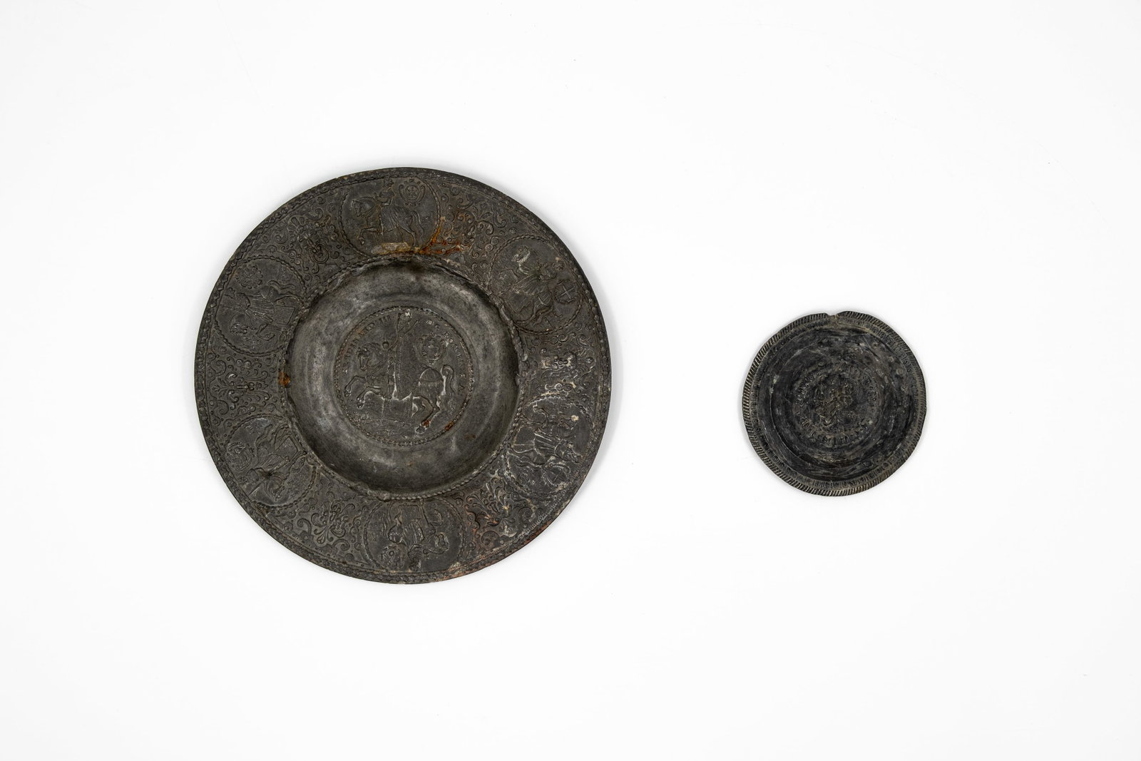 A composed lot of two antique bas reliëf various decorated repoussé pewter round plates: A composed lot of two antique bas reliëf variously decorated repoussé pewter round plates. 18th/19th century. W: 8,5 - 19 cm