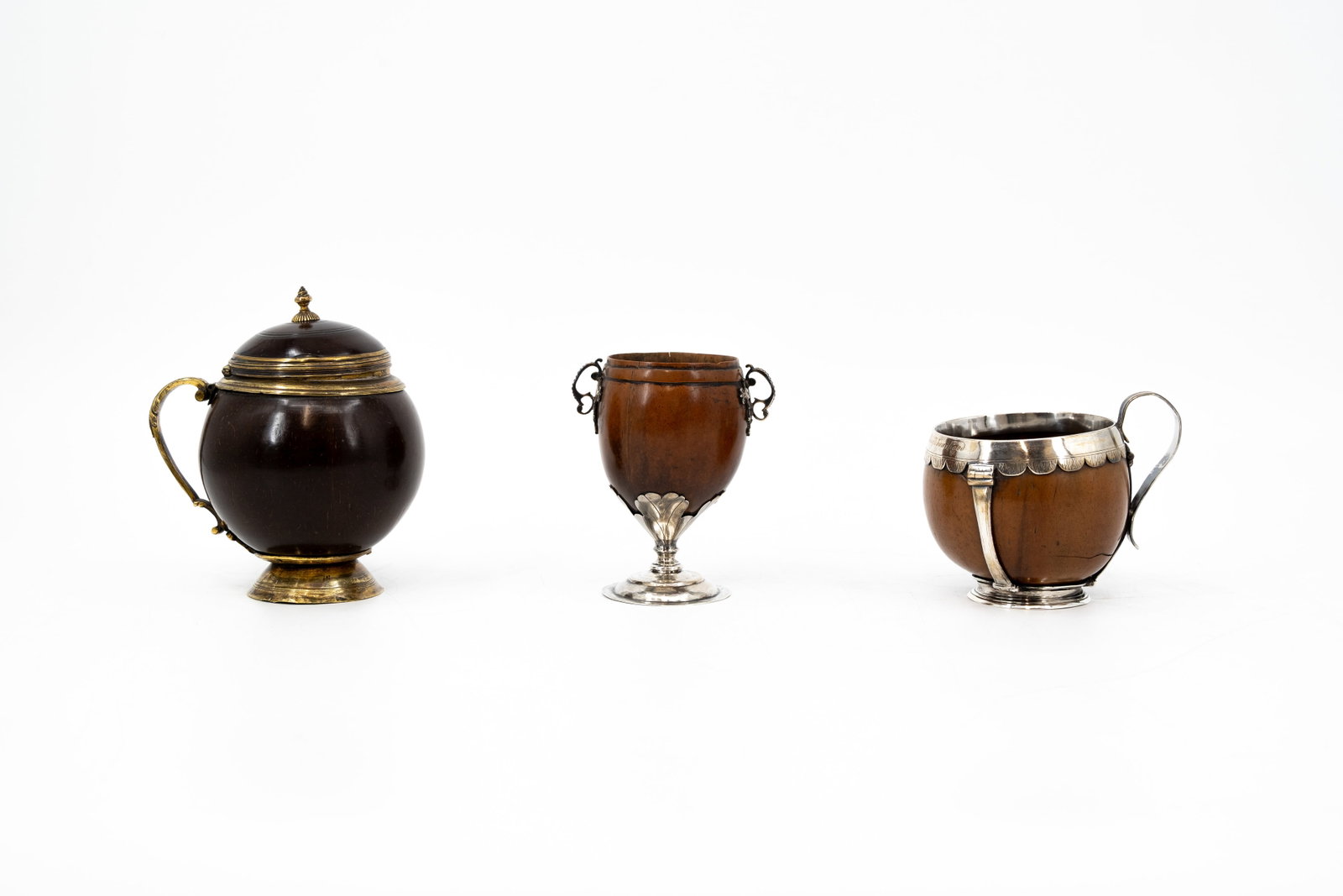 A composed lot of three antique with silver and brass mounted coconut cups: A composed lot of three antique with silver and brass mounted coconut cups. 18th/19th century. H: 10,3 - 11,5 - 14 cm