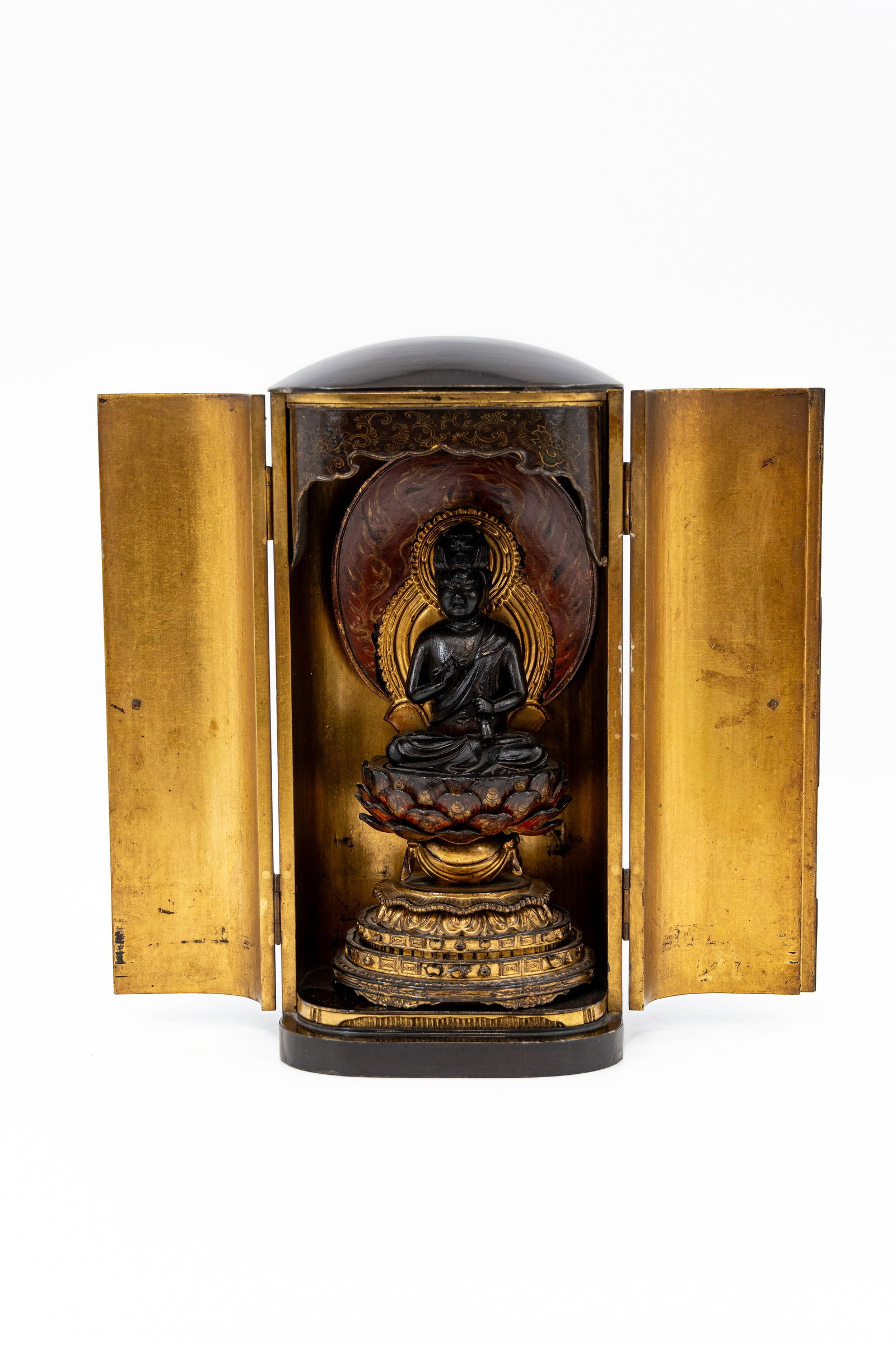 A Japanese, lacquered altar shrine with finely carved and decorated wooden figure of Buddha: A Japanese, lacquered altar shrine with finely carved and decorated wooden figure of Buddha, sitting on a lotus flower. Some damage to the flower, condition report available on request. Circa 1900. H: