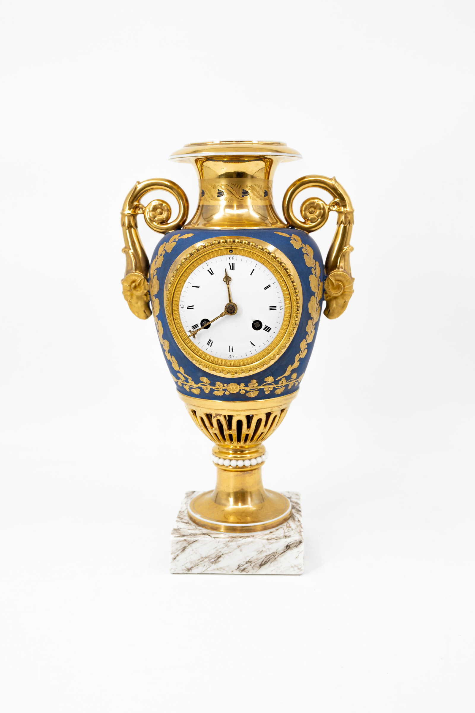 An antique Empire finely gilt decorated vase-shaped clock with ram-shaped handles: An antique Empire style finely gilt decorated vase-shaped clock with ram-shaped handles. Early 19th century. H: 37 - W: 20 cm