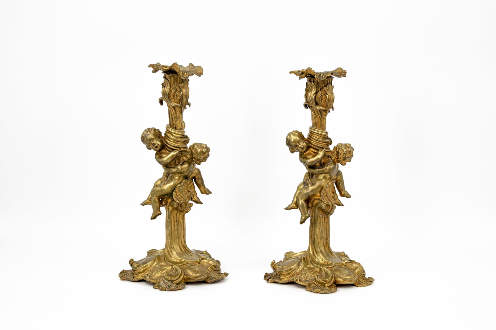 A pair of antique French baroque style gilt bronze figural candleholders: A pair of antique French baroque style gilt bronze figural candleholders with two putti, modelled after Juste Aurèle Meissonnier (1695-1750). 19th century. H: 33 cm