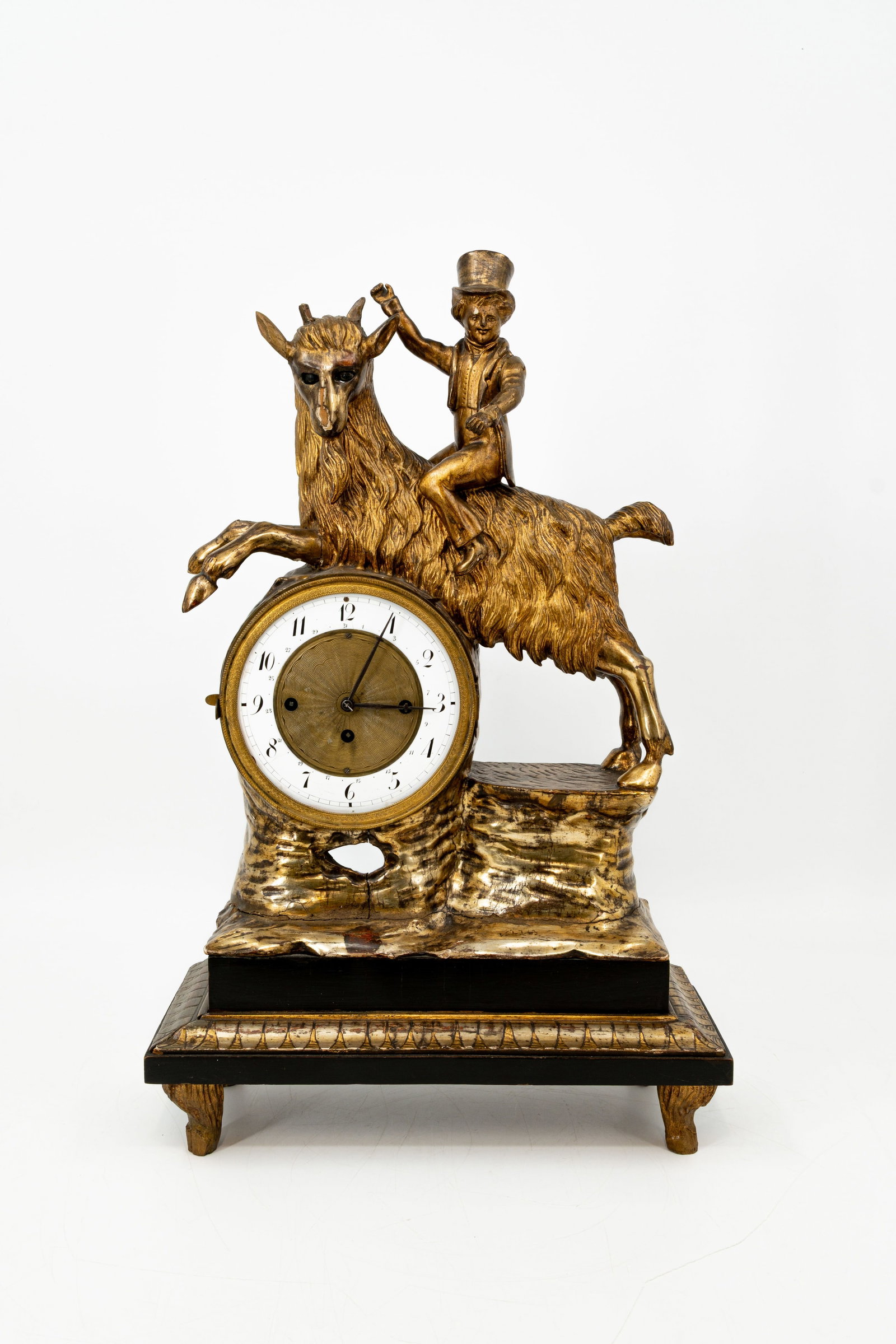 A rare antique polychrome-patinated carved wood automaton mantel clock: A rare antique polychrome-patinated carved wood automaton mantel clock with movable eyes and arms. Representing a boy with hat riding a goat. 19th century. H: 56 - W: 35 cm