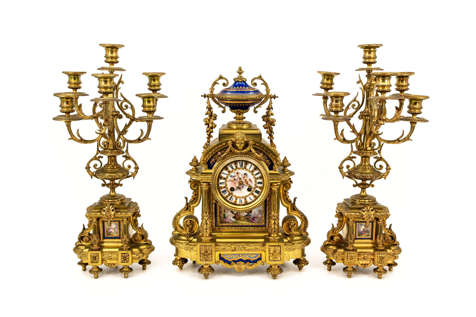 An antique gilt bronze and Sèvres-style porcelain mounted mantel clock with candelabra: An antique gilt bronze and Sevres-style porcelain mounted mantel clock and candelabras by H. LUPPENS - finely hand-painted with multiple romance scenes. Late 19th century. H: 46 - W: 32 cm, clock