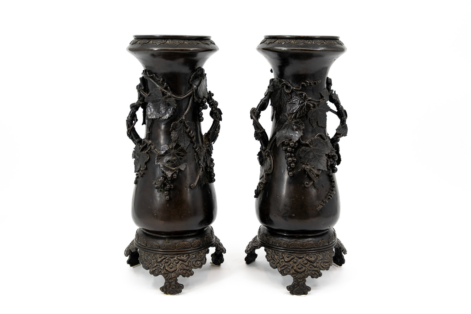 A pair of antique Japanese patinated and decorated vases: A pair of antique Japanese patinated reliëf grapes and leaf decorated vases with handles. Each vase is marked with two seals. Meiji, circa 1900. H: 36 cm