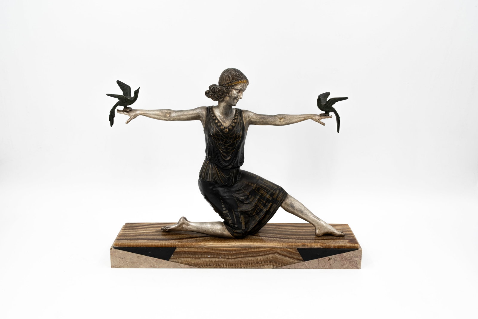 An art deco bi-color patinated spelter sculpture group: An art deco bi-color patinated spelter sculpture group of a lady with birds. Mounted on a onyx and black marble base. Unsigned, circa 1900-1920s. H: 34,5 - W: 44,5 cm