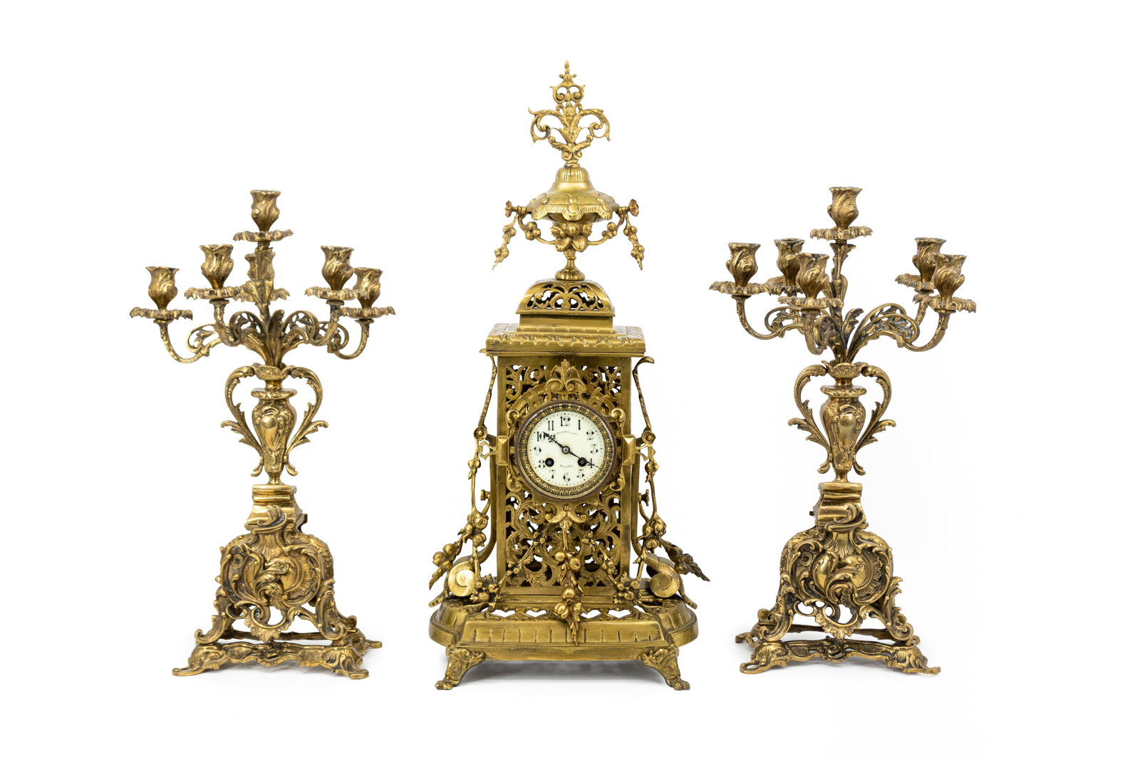 A large antique Baroque-style gilt brass mantel clock with two candelabra: A large antique Baroque-style gilt brass mantel clock with two candelabra. Circa 1900. H: 70,5 - W: 30 cm, clock