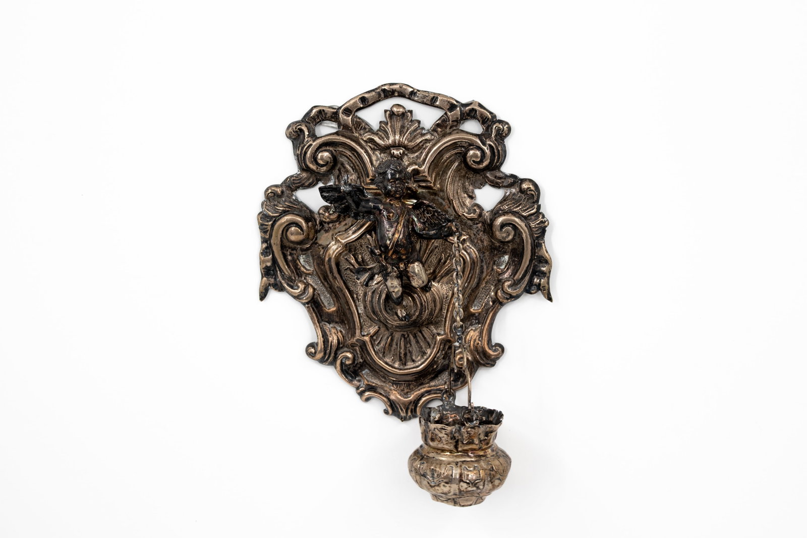 An antique religious decorated silver wall holy water font: An antique silver religious and richly decorated wall holy water font with a putti figurine. Unmarked, 19th/20th century. H: 22 - W: 19 cm, without bucket