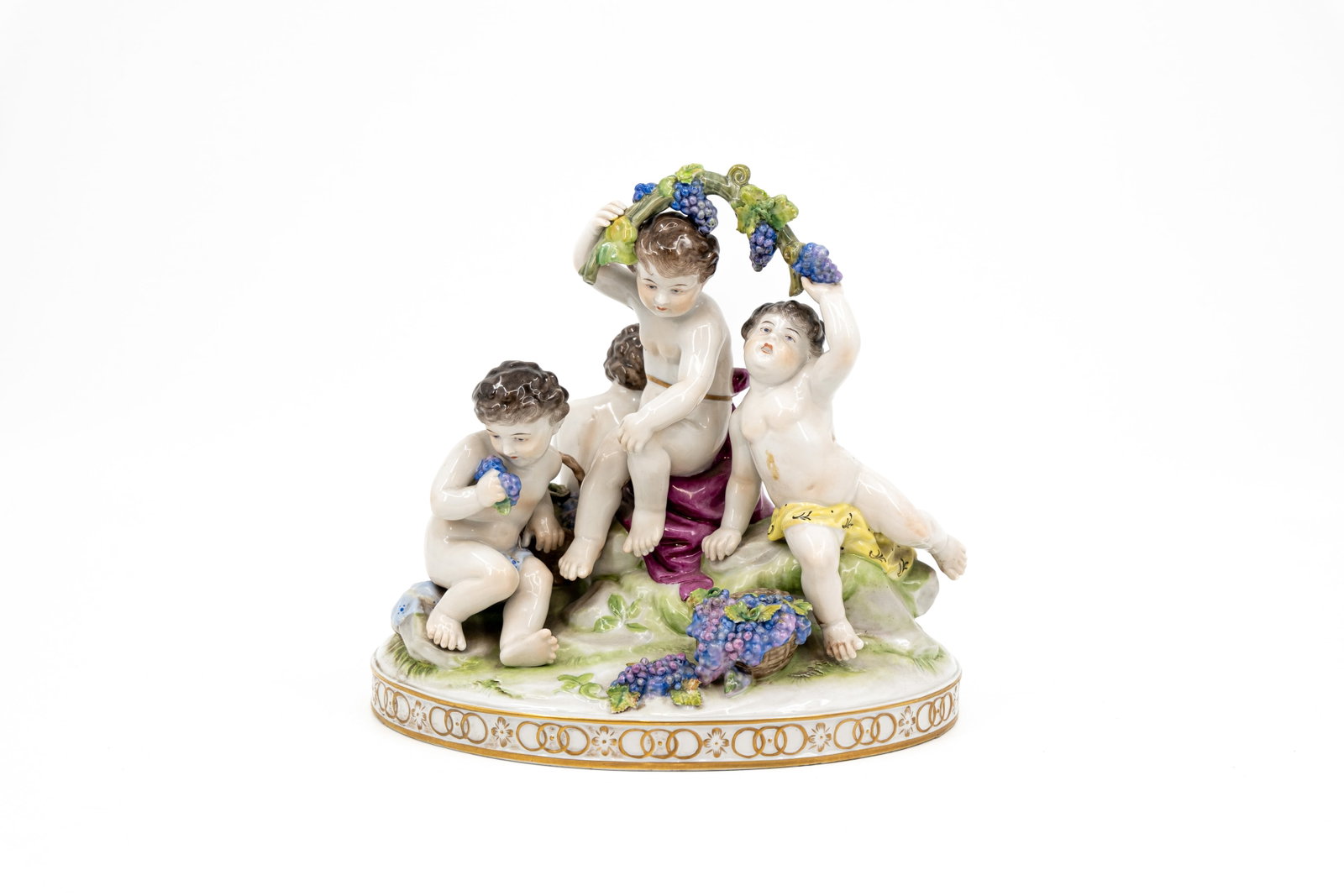 A German Volkstedt saxony style decorated porcelain figural group: A German Volkstedt saxony style decorated porcelain figural group of four putti with grapes. Marked, 20th century. H: 24 - W: 25,5 cm