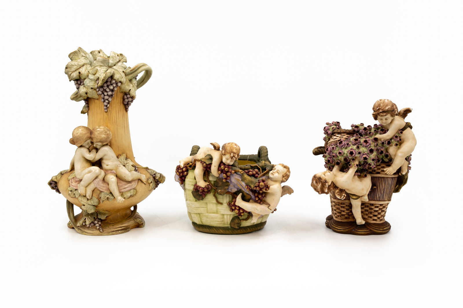 A composed lot of three Austria Amphora porcelain basket vases: A composed lot of three Austria Amphora porcelain basket vases decorated with putti or children, one basket shaped vase decorated with putti, one basket shaped planter decorated with putti and one vas