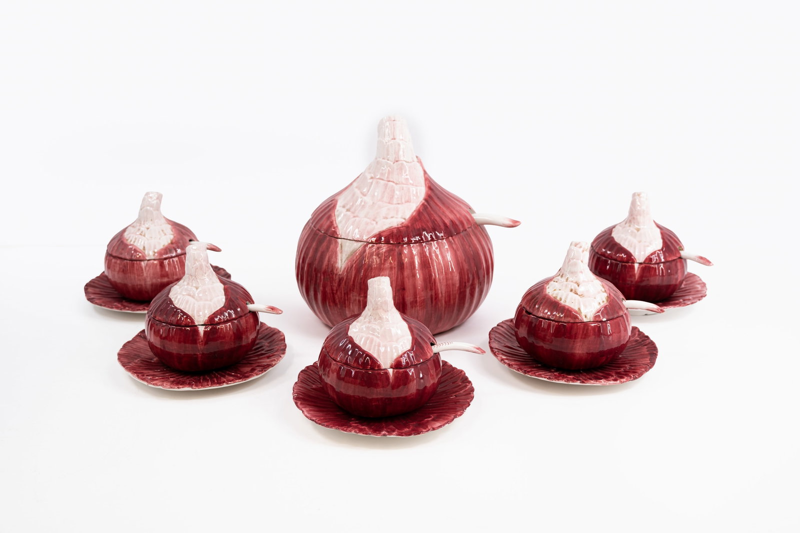 A set of five glazed ceramic red onion shaped covered bowls and their matching tureen: A red onion shaped soup set in glazed ceramic. Consisting of: one tureen with matching ladle and five covered soup bowls with matching spoons. Probably French made, circa 1950s. H: 26 - W: 25 cm, ture