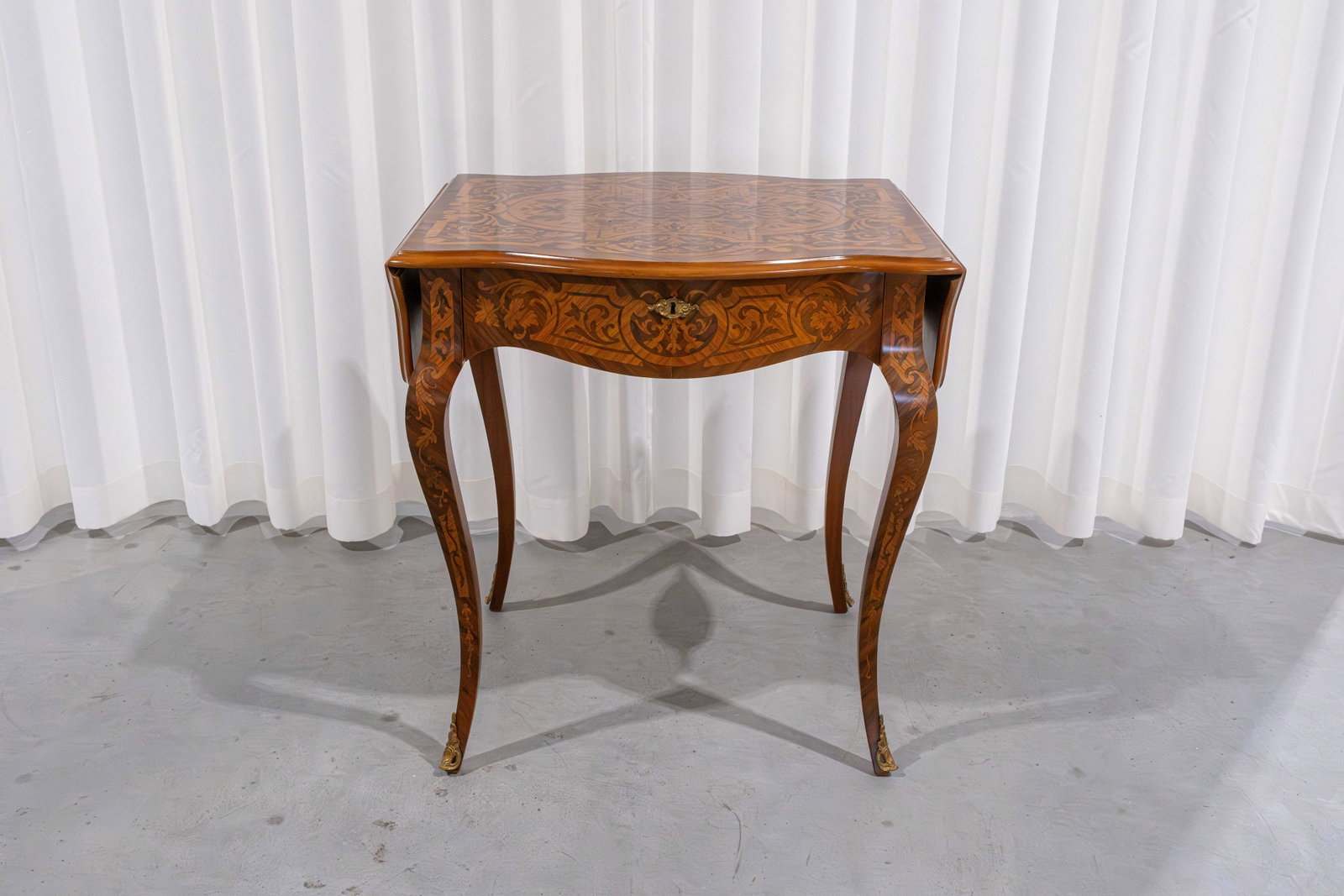 A 20th century Louis XV-style brass-mounted folding table with marquetry inlay: A 20th century Louis XV-style brass-mounted folding table with marquetry inlay and one drawer. Circa 1970s. H: 72 - W: 67 - D: 60 cm, closed