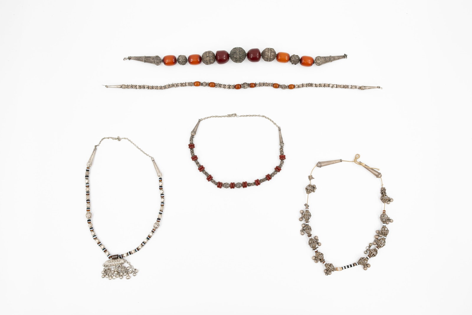 A composed lot of five various amber colored silver mounted necklaces and jewelry: A composed lot of five various amber colored and silver mounted necklaces and jewelry. 19th/20th century. Total weight: 693 gr.