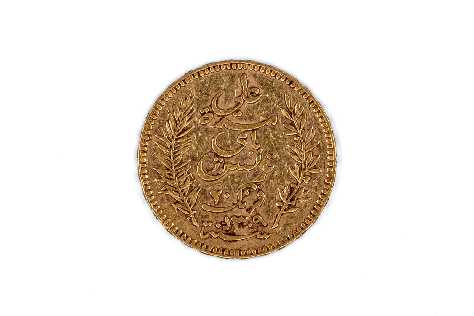 A Tunisian gold 20 Francs coin, dated 1892: A Tunisian gold 20 Francs coin, dated 1892. With Arabic inscription within wreath on the obverse, and denomination and date within ornamental border on the reverse. Weight: 6,4g