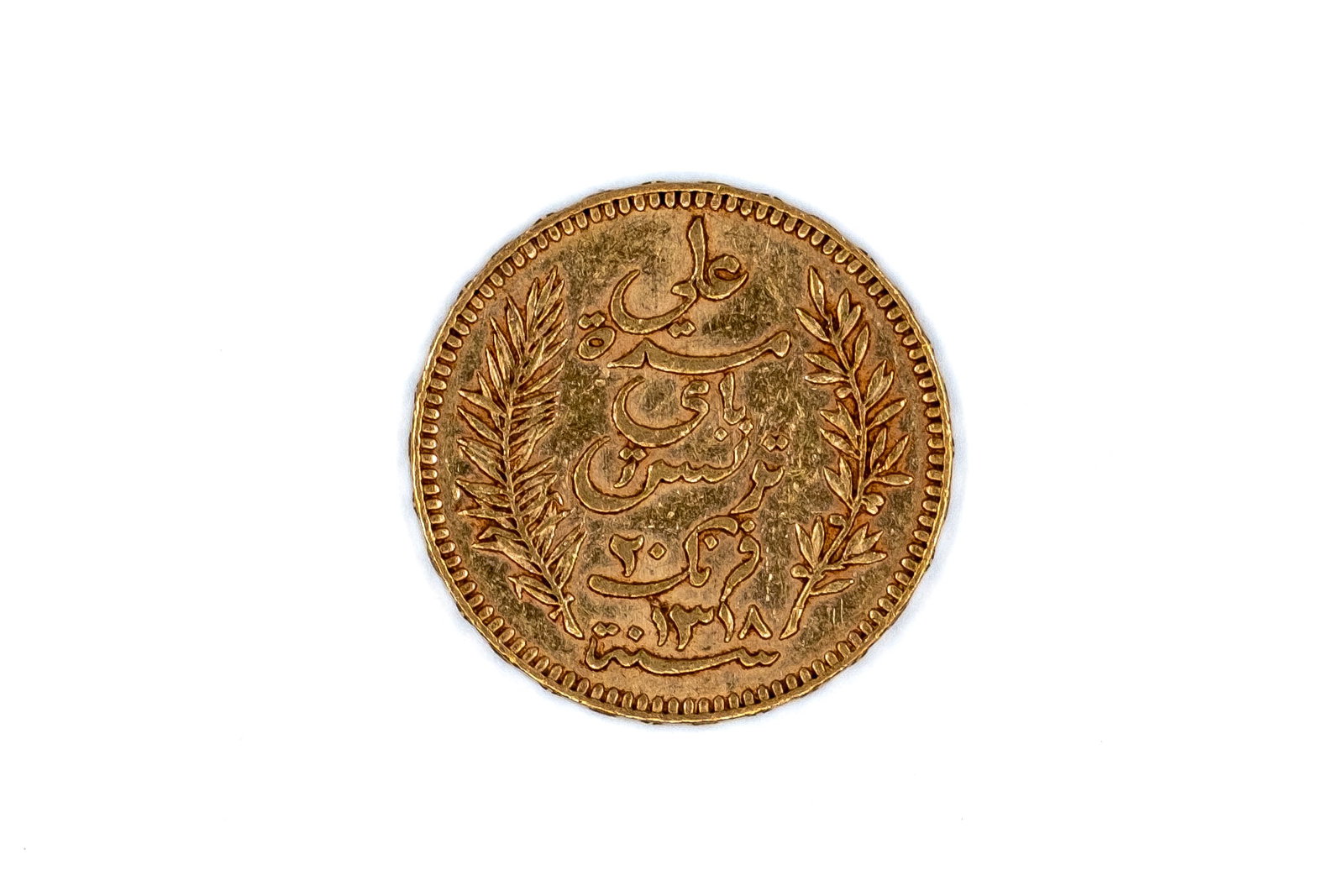 A Tunisian gold 20 Francs coin, dated 1900: A Tunisian gold 20 Francs coin, dated 1900. With Arabic inscription within wreath on the obverse, and denomination and date within ornamental border on the reverse. Weight: 6,4g
