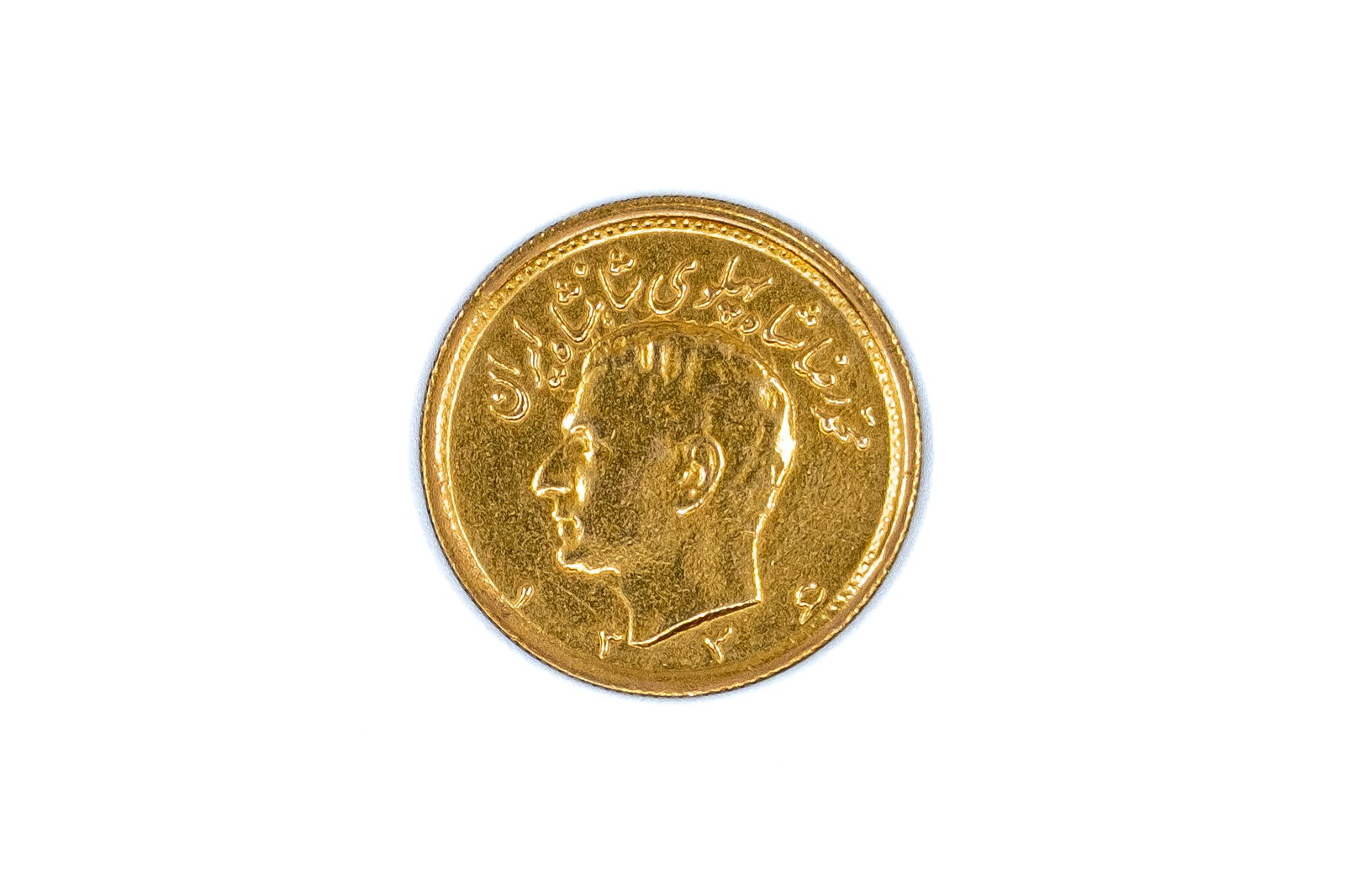 An Iranian gold half pahlavi, Reza Shah Pahlavi: An Iranian gold half pahlavi, Reza Shah Pahlavi. With portrait of Reza Shah Pahlavi and Persian legend on the obverse, and crowned lion and sun motif within wreath on the reverse. Weight: 4g