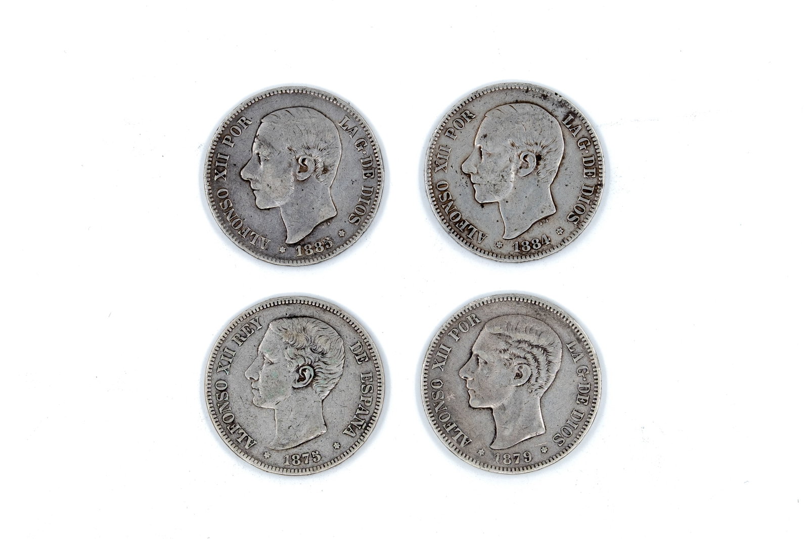 A lot of four Spanish silver 5 Pesetas coins of Alfonso XII: A lot of four Spanish silver 5 Pesetas coins of Alfonso XII, dated 1875, 1879, 1884, and 1885. With portrait of the king on the obverse and crowned Spanish coat of arms between pillars on the reverse.