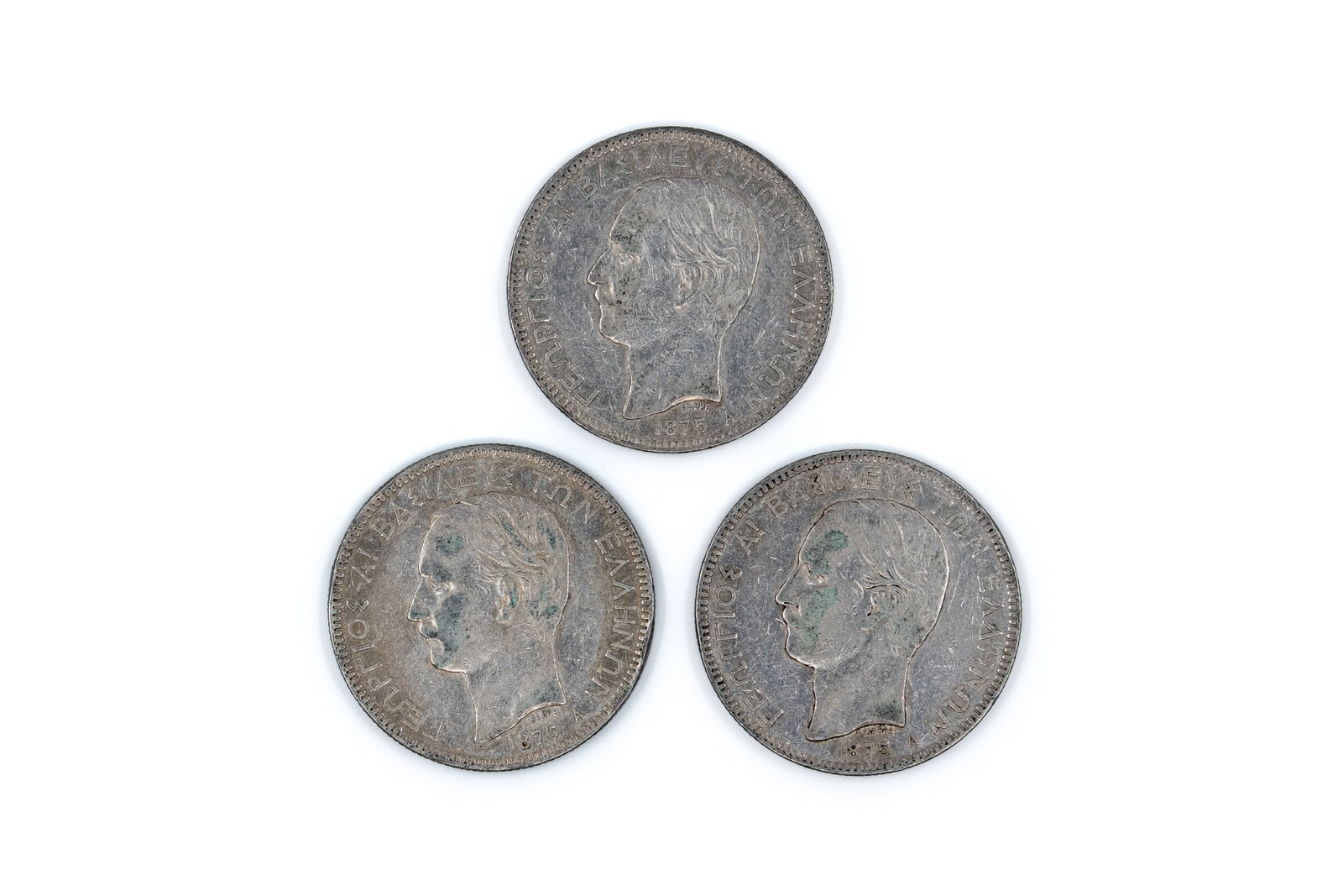 A lot of three Greek silver 5 Drachmai coins of George I, dated 1875-1876: A lot of three Greek silver 5 Drachmai coins of George I, dated 1875-1876. Comprising portrait issues of the king facing left, with Greek legend on the obverse, and crowned arms within a wreath with d