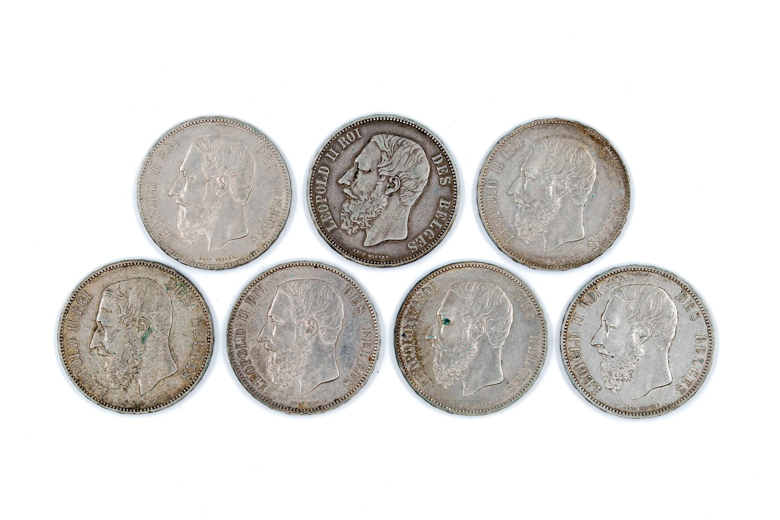 A lot of seven Belgian silver 5 Francs coins of Leopold II, dated 1867-1876: A lot of seven Belgian silver 5 Francs coins of Leopold II, dated 1867-1876. All coins with obverses depicting Leopold II facing left, and the reverse showing the crowned Belgian coat of arms within a