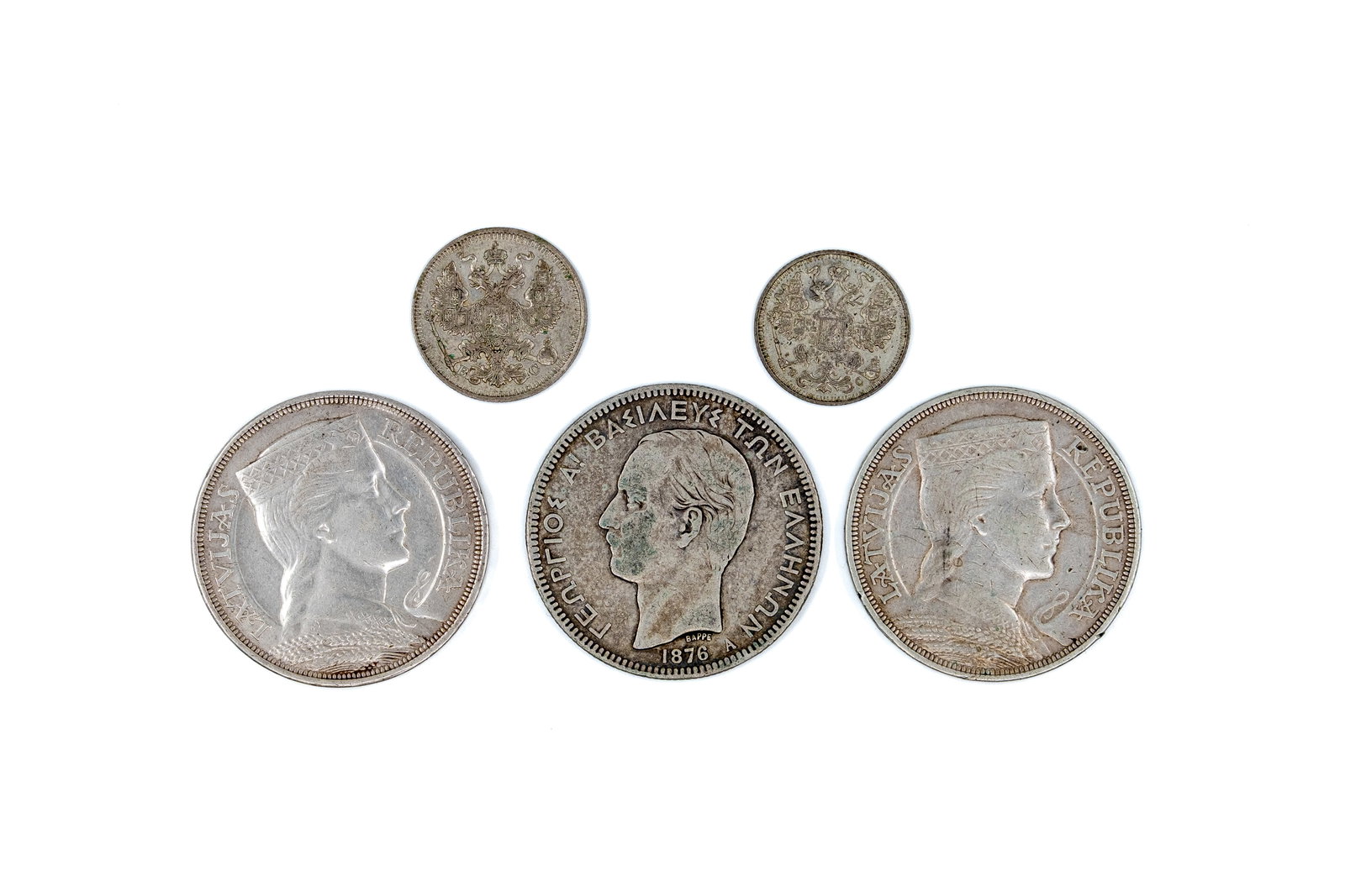 A lot of five silver coins from various countries: A lot of five silver coins, comprising Russian 15 and 20 Kopeks issues dated 1914-1917, a Greek 5 Drachmai coin of George I dated 1876, and two Latvian 5 Lati coins. Including imperial Russian double-