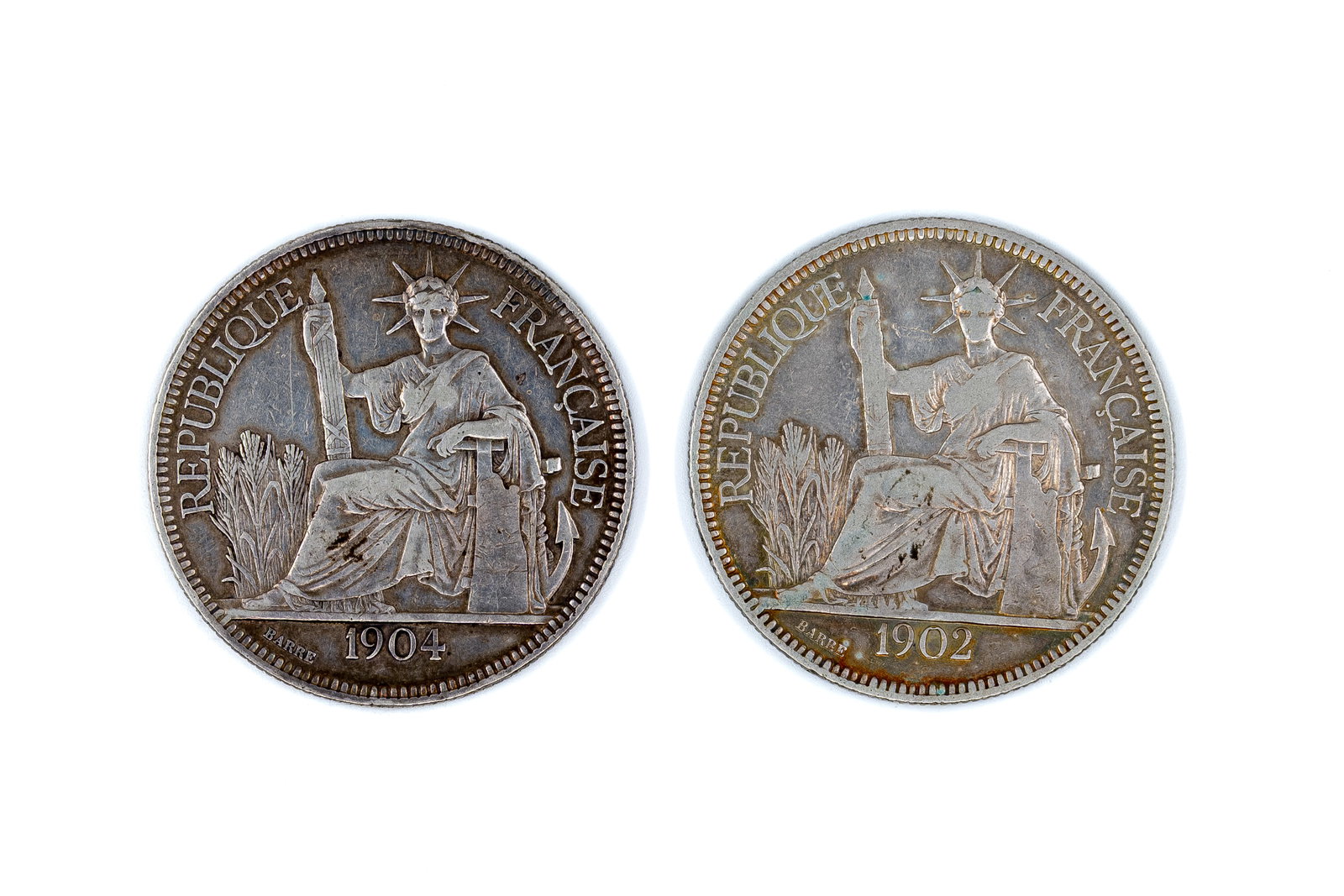 A lot of two French Indochina silver piastres de commerce, dated 1902 and 1904: A lot of two French Indochina silver piastres de commerce, dated 1902 and 1904. Both issues with seated figure of Liberty on the obverse and wreath with denomination reverse. Weight: 27 - 26,8g