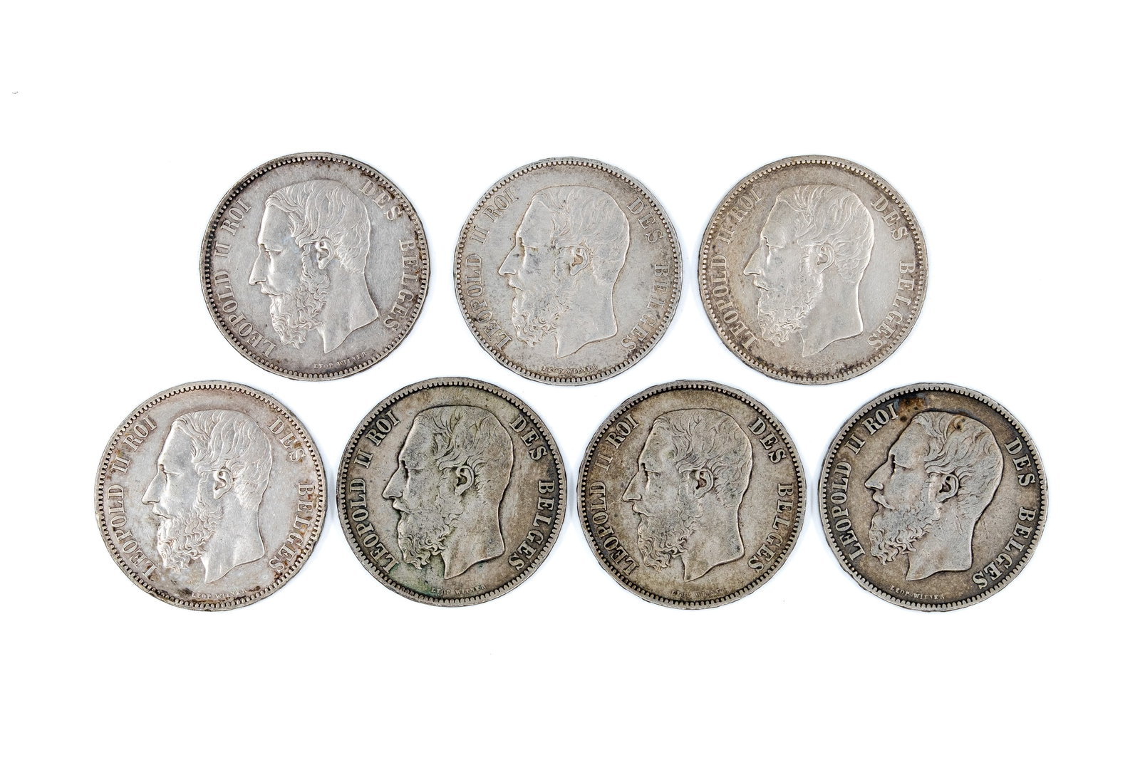 A lot of seven Belgian silver 5 Francs coins of Leopold II, dated 1867-1875: A lot of seven Belgian silver 5 Francs coins of Leopold II, dated 1867-1875. All issues of Leopold II, with crowned coat of arms within wreath reverse. Total weight: 174g