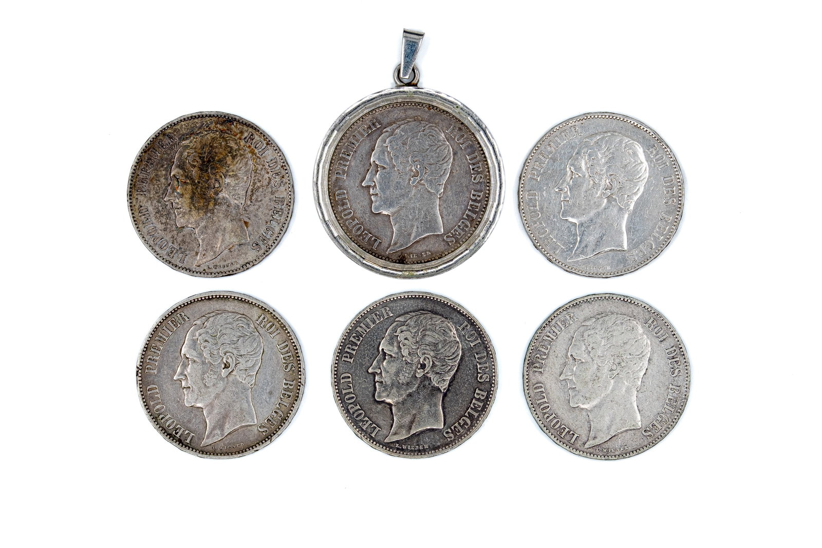 A lot of seven Belgian silver 5 Francs coins of Leopold I, dated 1849-1865: A lot of seven Belgian silver 5 Francs coins of Leopold I, dated 1849-1865. All issues of Leopold I, including one mounted piece, all with crowned coat of arms within wreath reverse. Total weight: 161