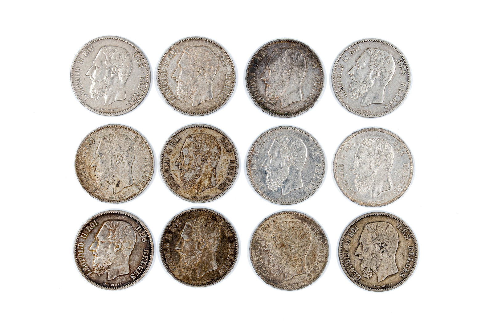 A lot of 12 Belgian silver 5 Francs coins of Leopold II, dated 1868-1876: A lot of 12 Belgian silver 5 Francs coins of Leopold II, dated 1868-1876. Comprising all silver issues with crowned shield reverse within wreath. Total weight: 298,8g