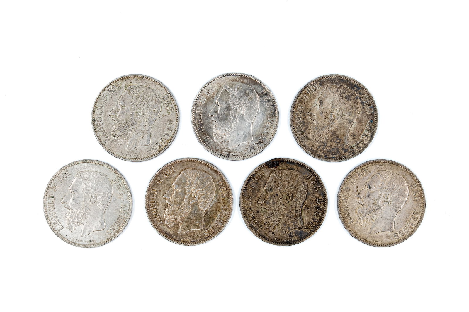 A lot of seven Belgian silver 5 Francs coins of Leopold II, dated 1870-1876: A lot of seven Belgian silver 5 Francs coins of Leopold II, dated 1870-1876. Comprising all silver issues with crowned shield reverse within wreath. Total weight: 175g