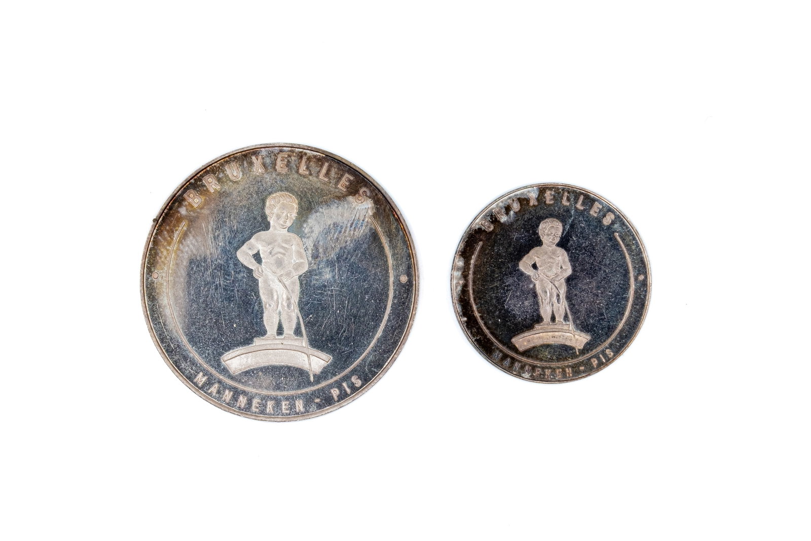 A lot of two Belgian Expo 58 medals featuring Manneken Pis: A lot of two Belgian Expo 58 medals featuring Manneken Pis. Comprising two Brussels World Exhibition pieces in different sizes, with Manneken Pis and globe design. Weight: 9,6 - 4,7g